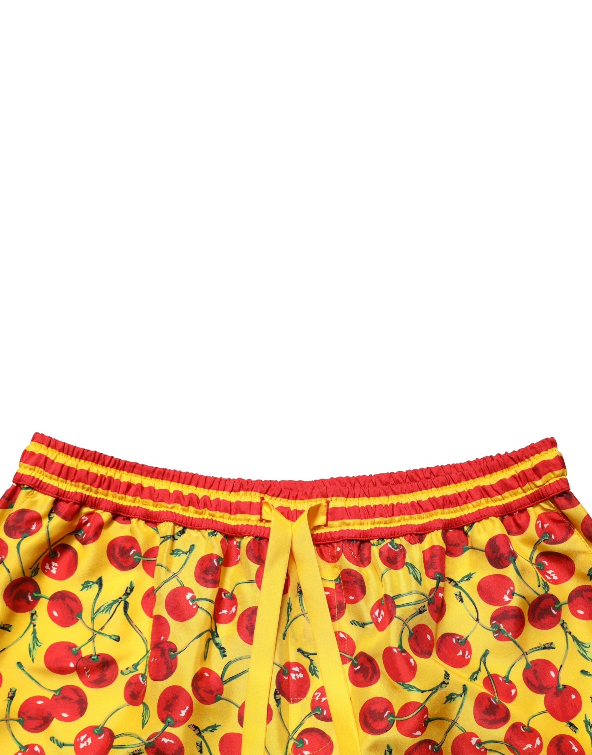 Shorts en soie Dolce & Gabbana à imprimé cerises jaunes et rouges, style bermuda, visible avec détails colorés et tissu léger.