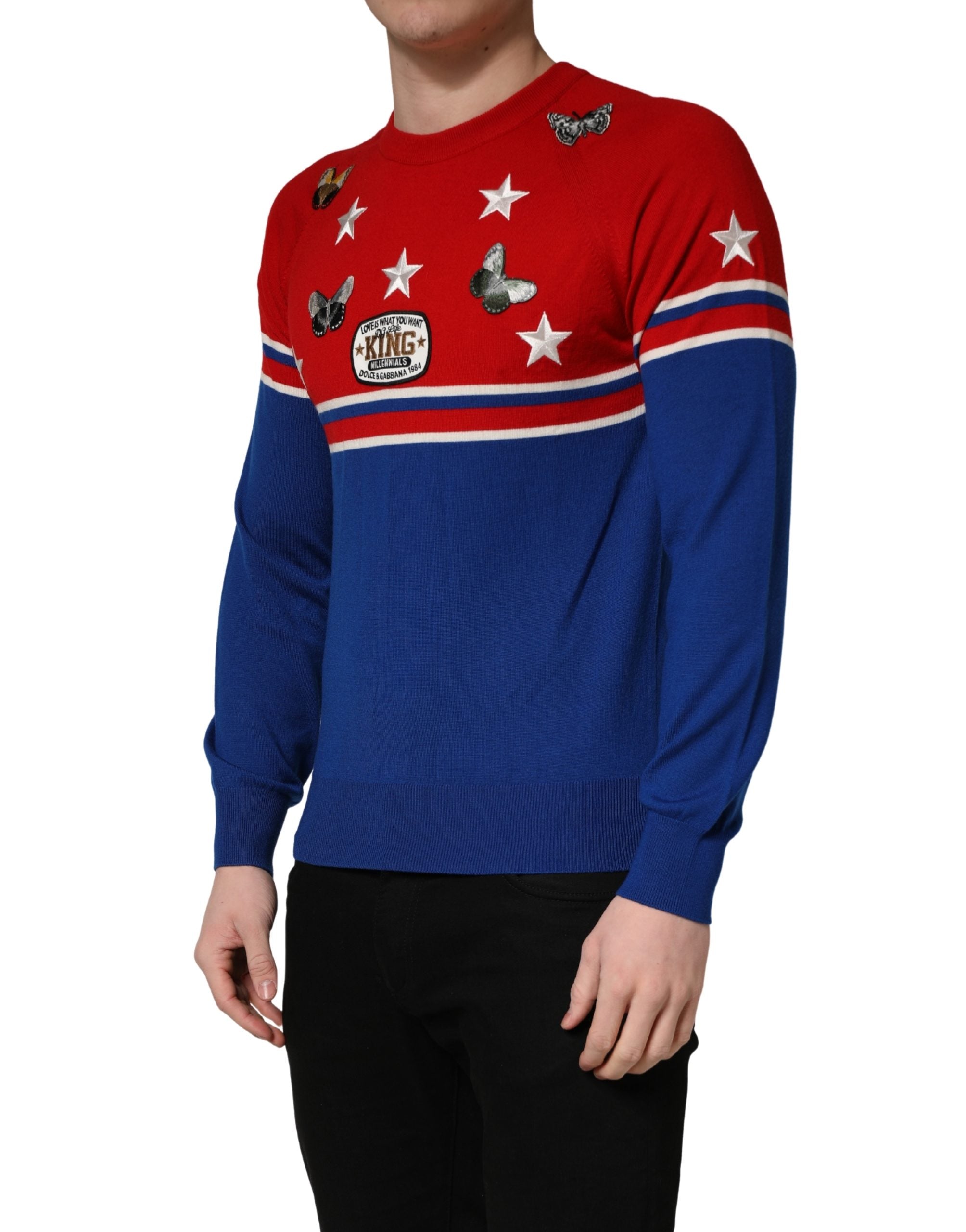 Pull homme Dolce & Gabbana en laine multicolore avec motif papillon et étoile, col ras du cou, visible sur l’image.