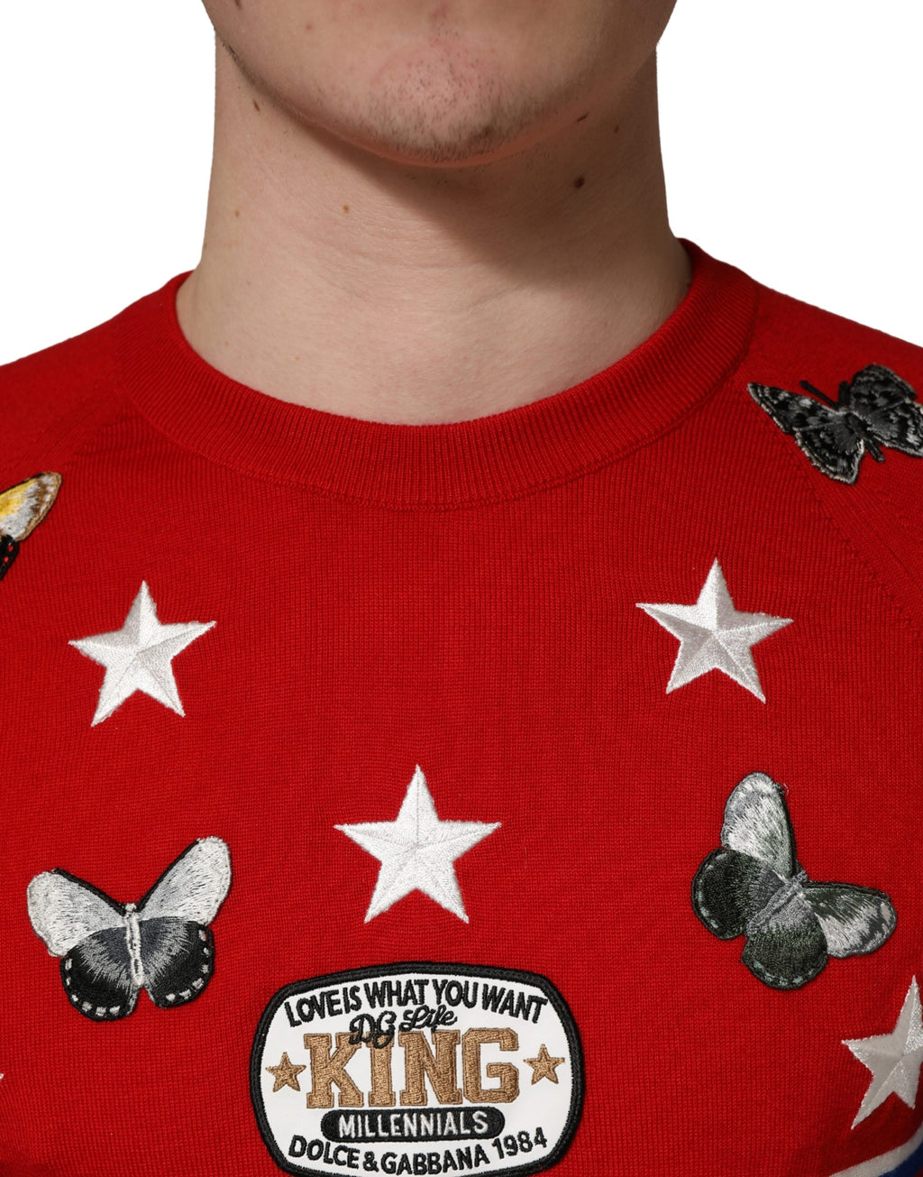 Pull homme Dolce & Gabbana en laine multicolore avec motifs papillon et étoile, col ras du cou, vue de face.