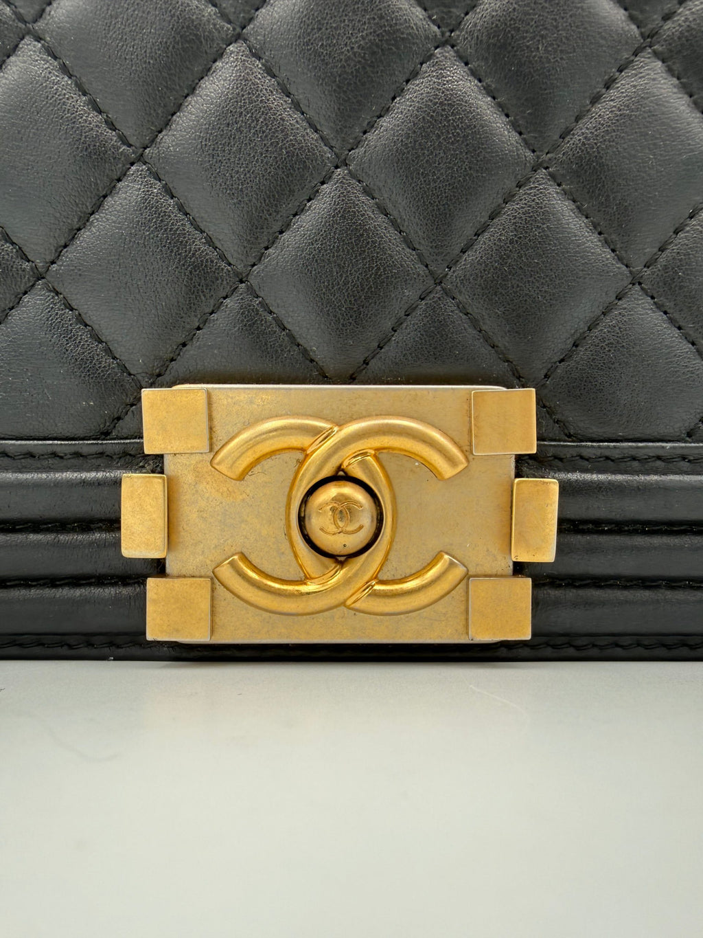 Grand sac à main Chanel Boy en cuir noir avec chaîne métallique, porté à la main, élégant et sophistiqué.