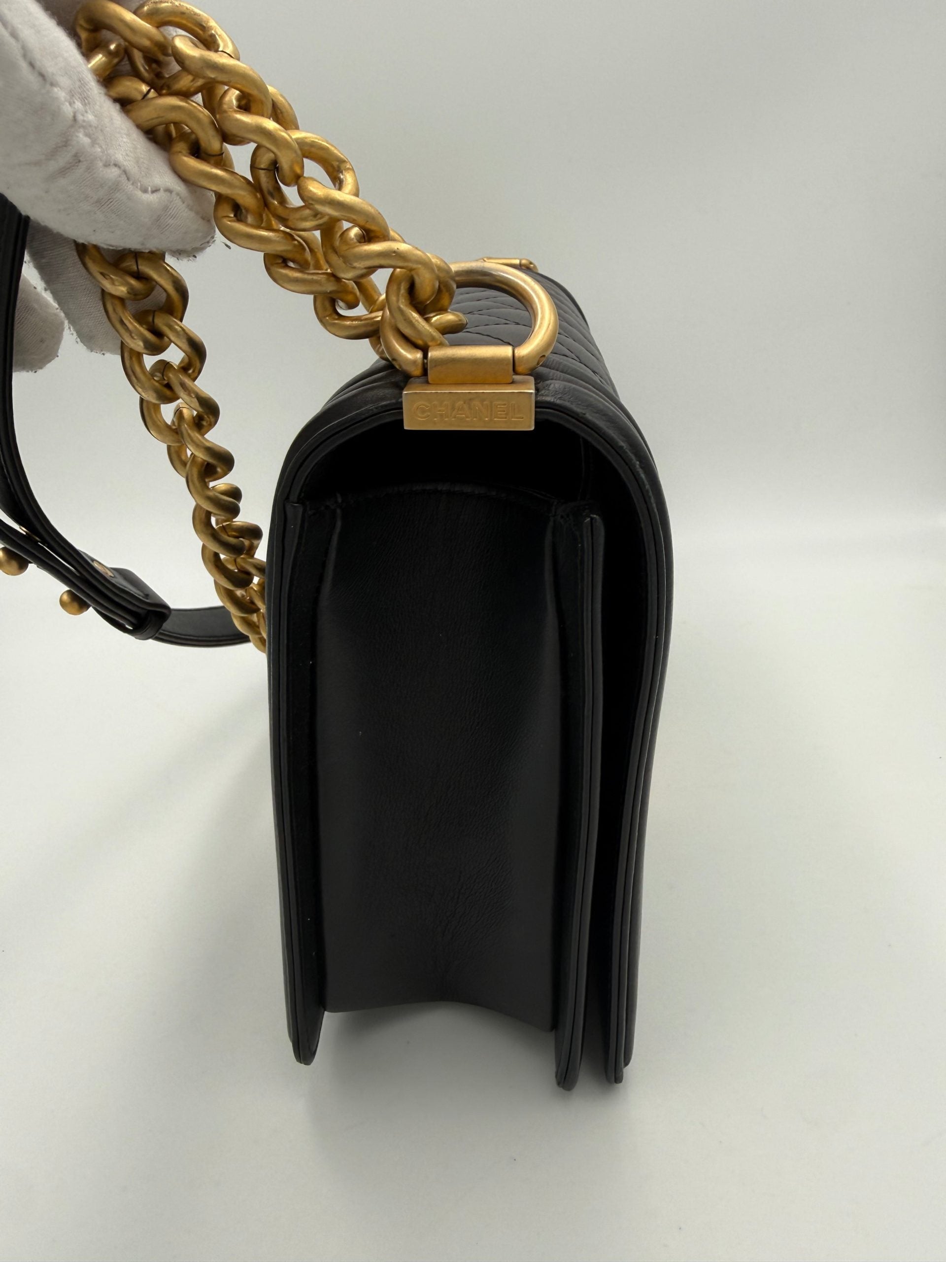 Sac à main Chanel Boy grand modèle en cuir noir avec chaîne métallique, vue en gros plan.