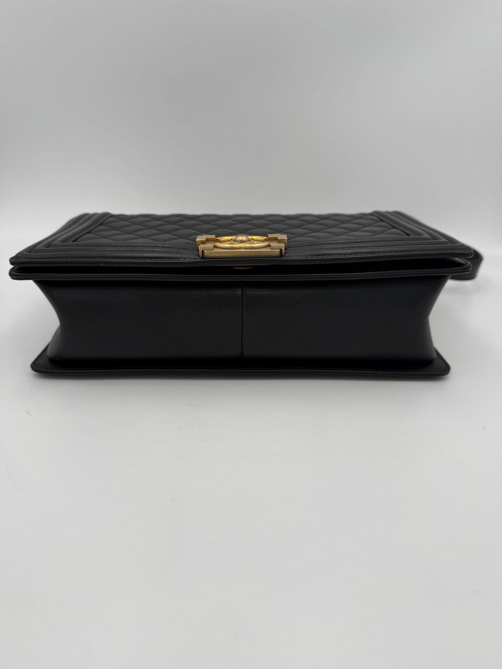 Grand sac à main Chanel Boy de grande taille, en cuir noir avec chaîne en métal et logo Chanel visible.