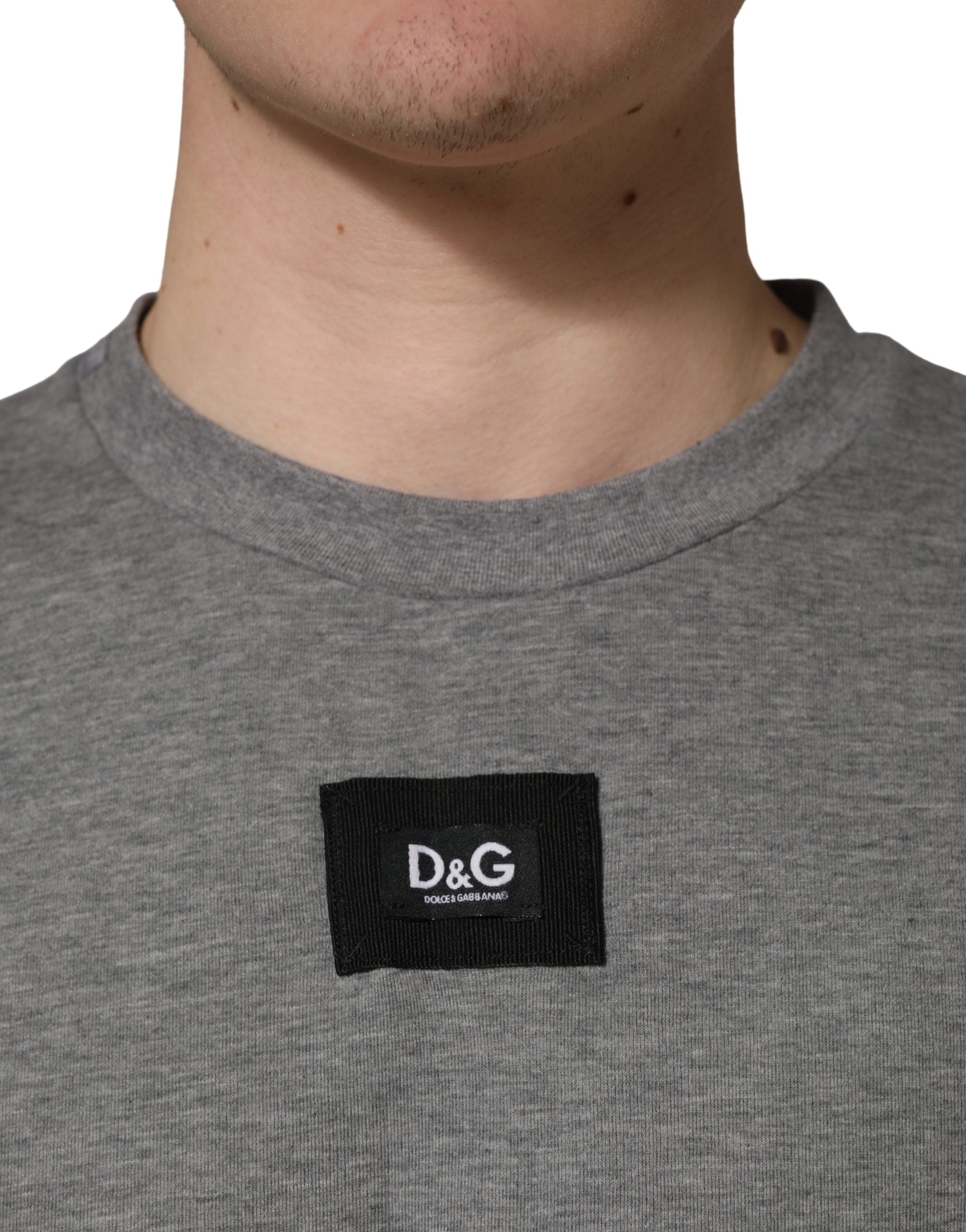 T-shirt gris en coton Dolce & Gabbana, avec logo et appliqué sur le col ras du cou, vue de face.