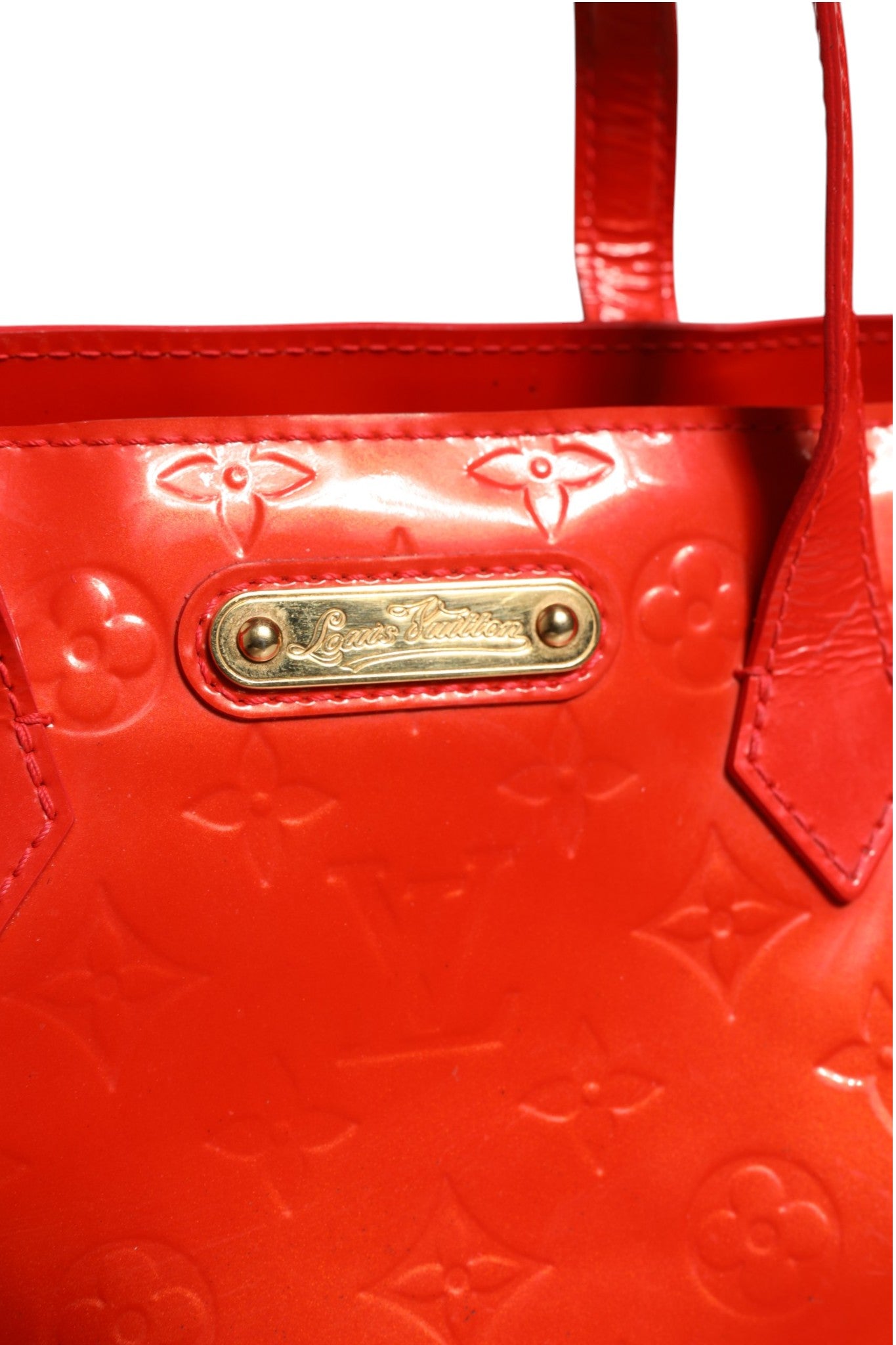 Sac Louis Vuitton Wilshire PM en vernis rouge à monogramme, avec détails élégants et poignées en cuir.