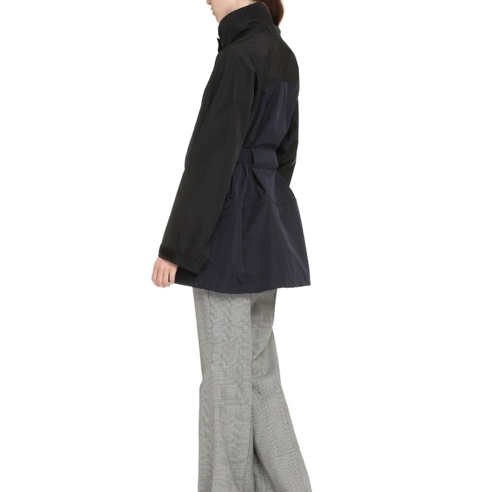Veste en polyamide bleue Prada, coupe-vent légère avec capuche, détails modernes et logo Prada visible sur la poitrine.