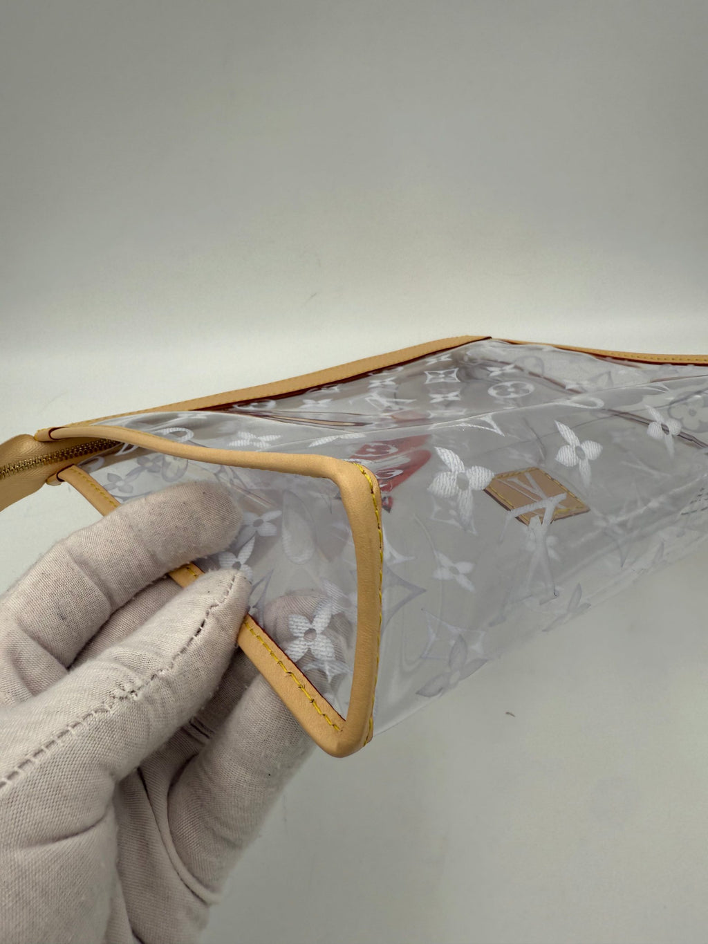 Pochette transparente Monogram de Louis Vuitton avec logo emblématique, en cuir verni et design élégant.
