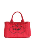 Sac Prada Canapa Mini en toile, sac à main compact avec poignées en cuir et logo Prada visible sur le devant.