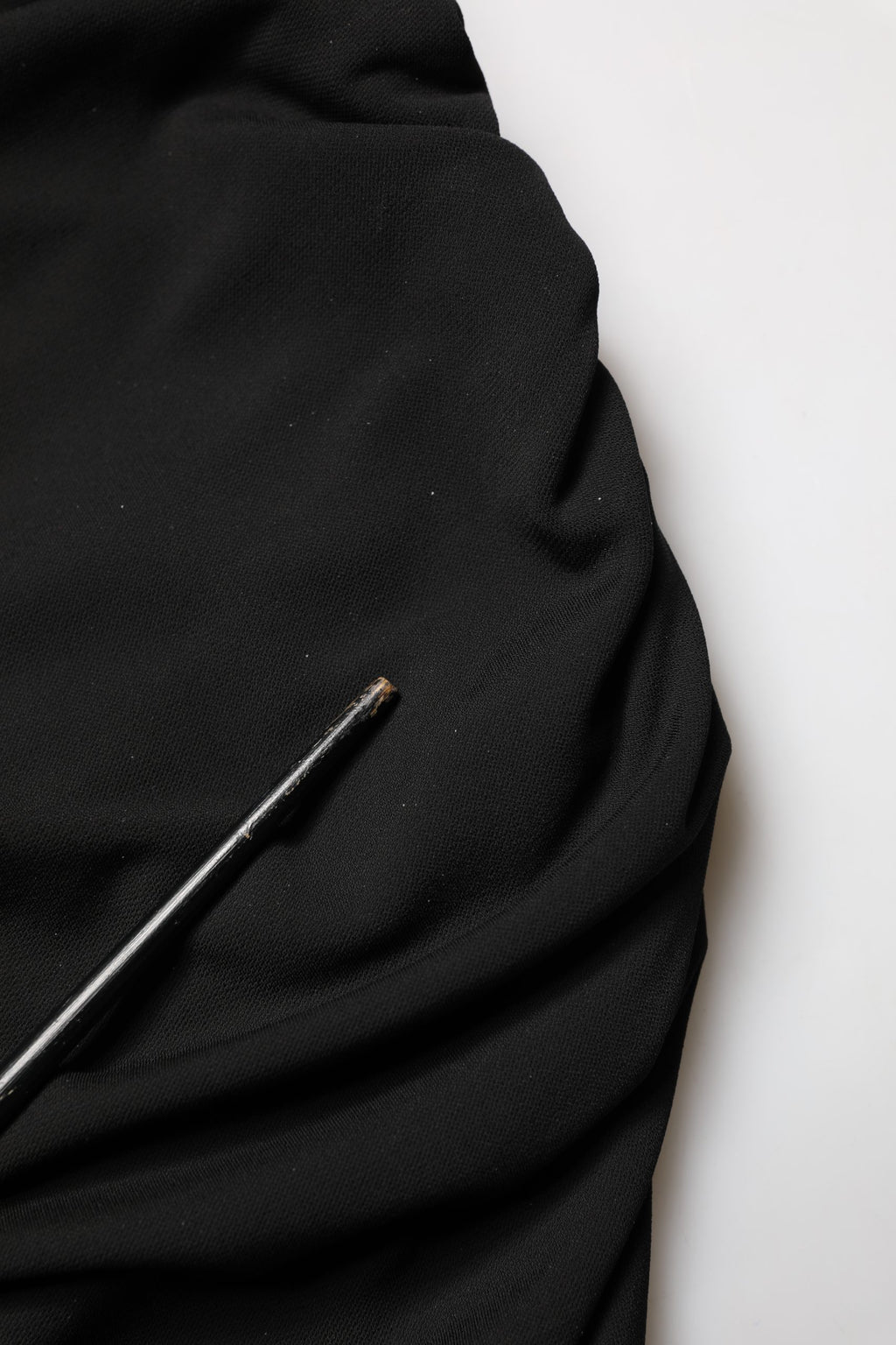 Robe noire en jersey Dolce & Gabbana, longueur mollet, avec découpes et drapés élégants, vêtement de soirée sophistiqué.