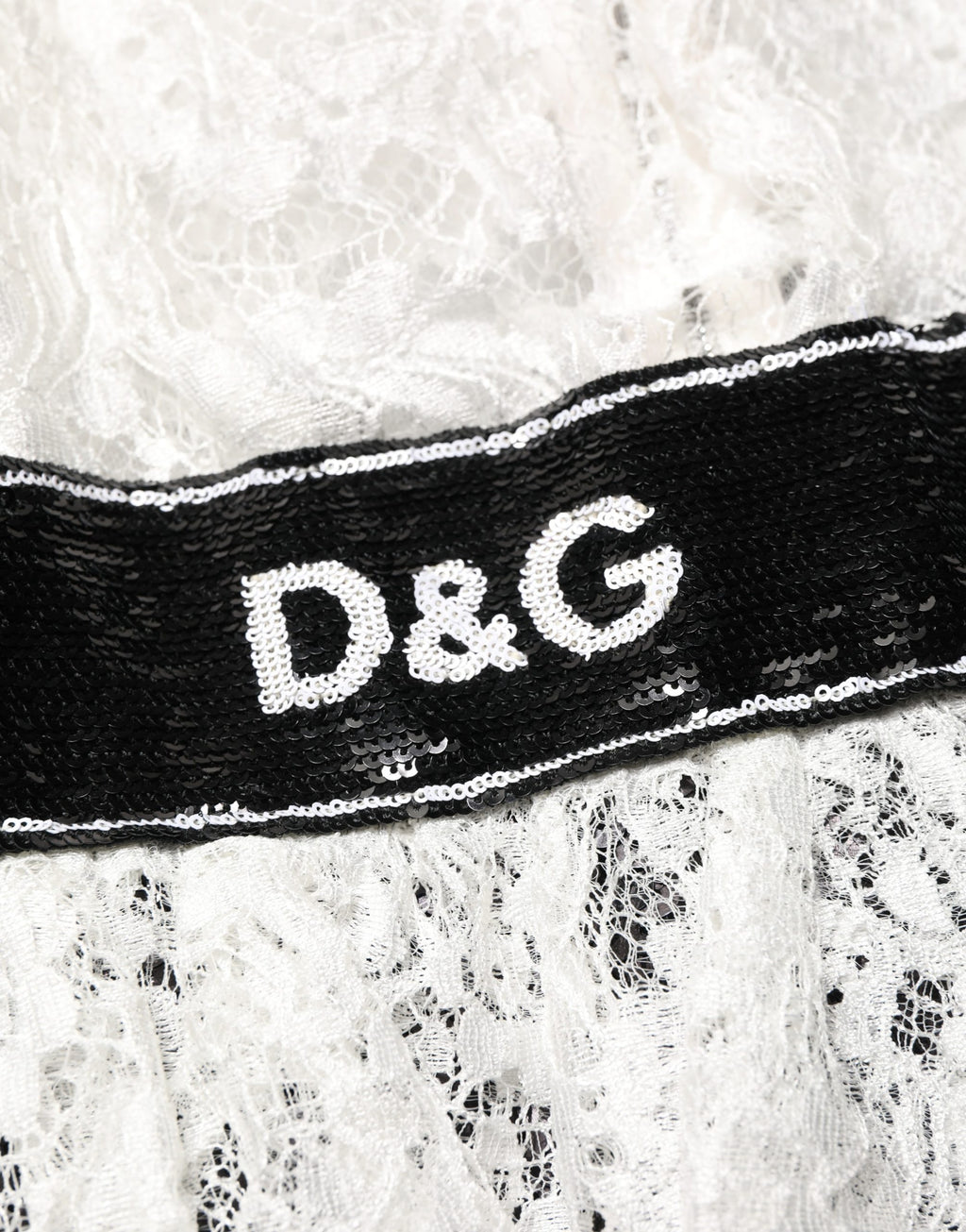 Robe Dolce & Gabbana blanche en dentelle avec embellissements, comprenant un haut en dentelle blanc et une jupe noire élégante.