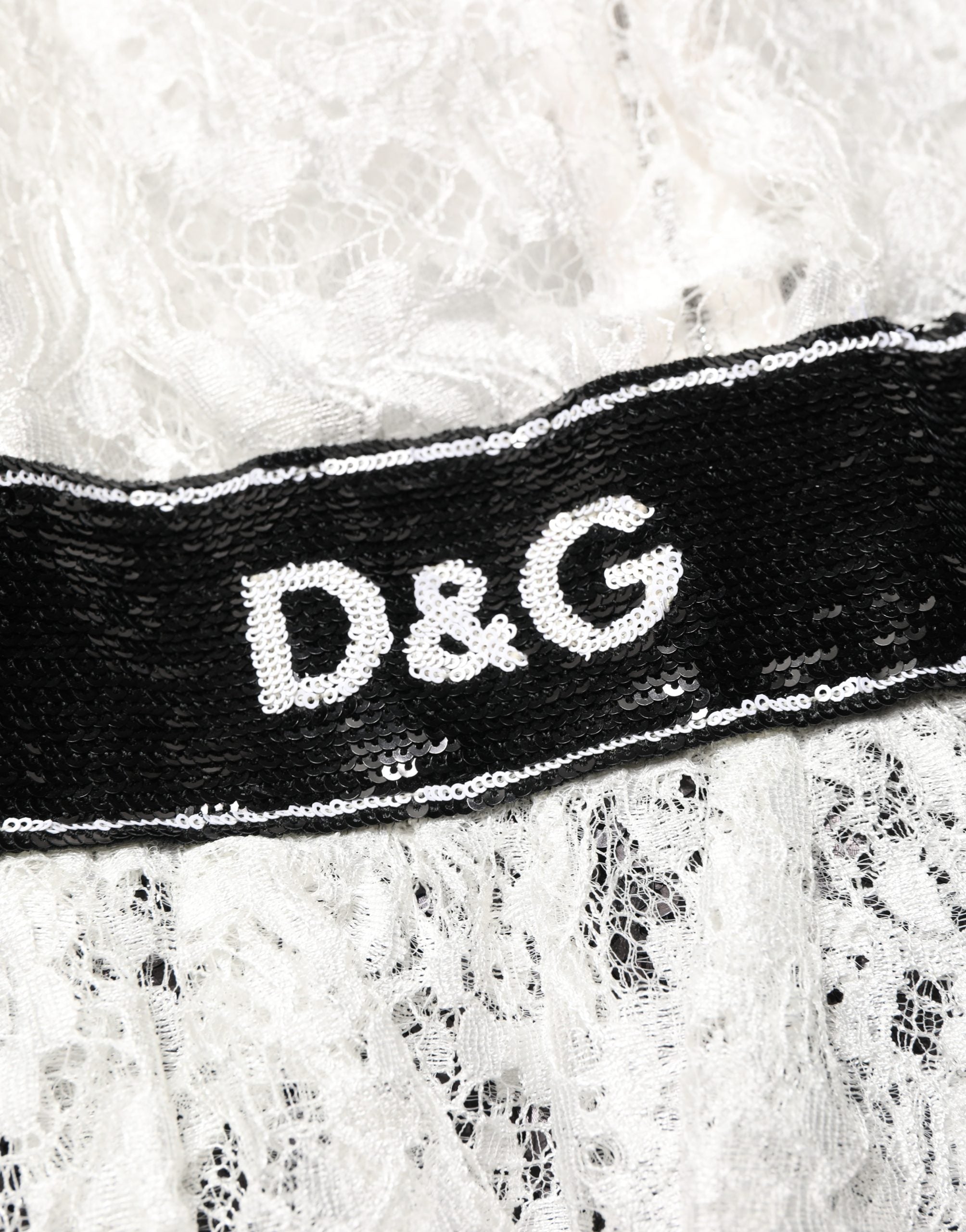 Robe Dolce & Gabbana blanche en dentelle avec embellissements, comprenant un haut en dentelle blanc et une jupe noire élégante.