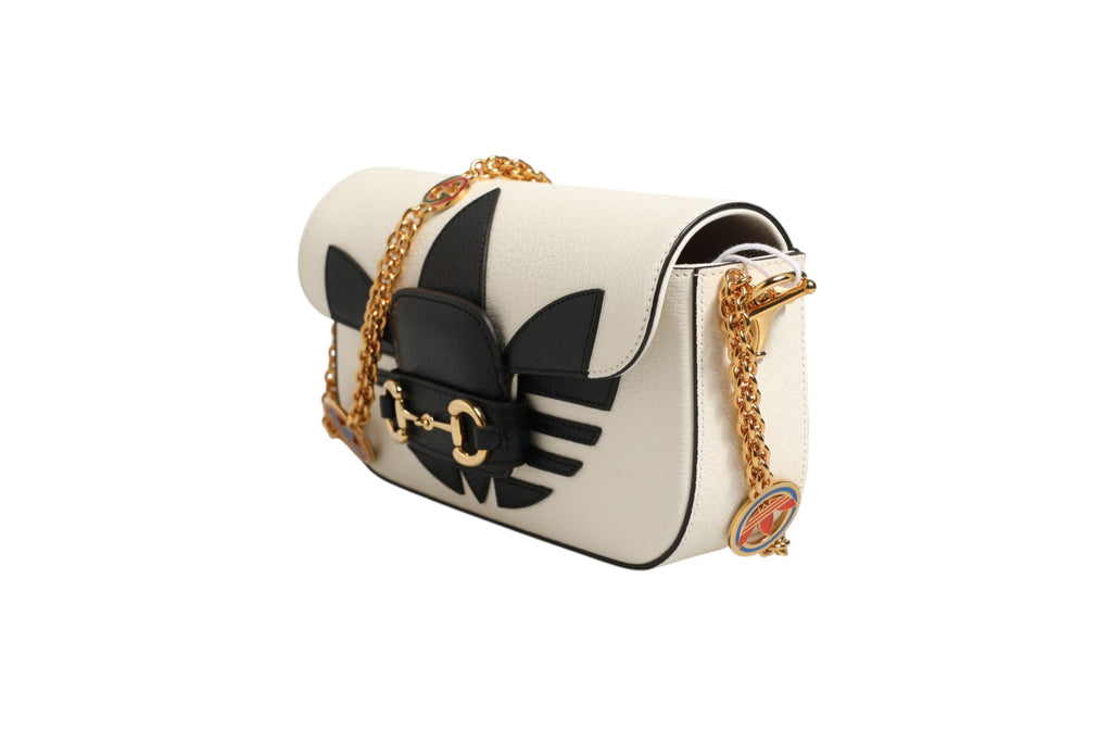Sac à bandoulière Gucci x Adidas Horsebit 1955 en noir et blanc, élégant avec détails en or et design moderne.
