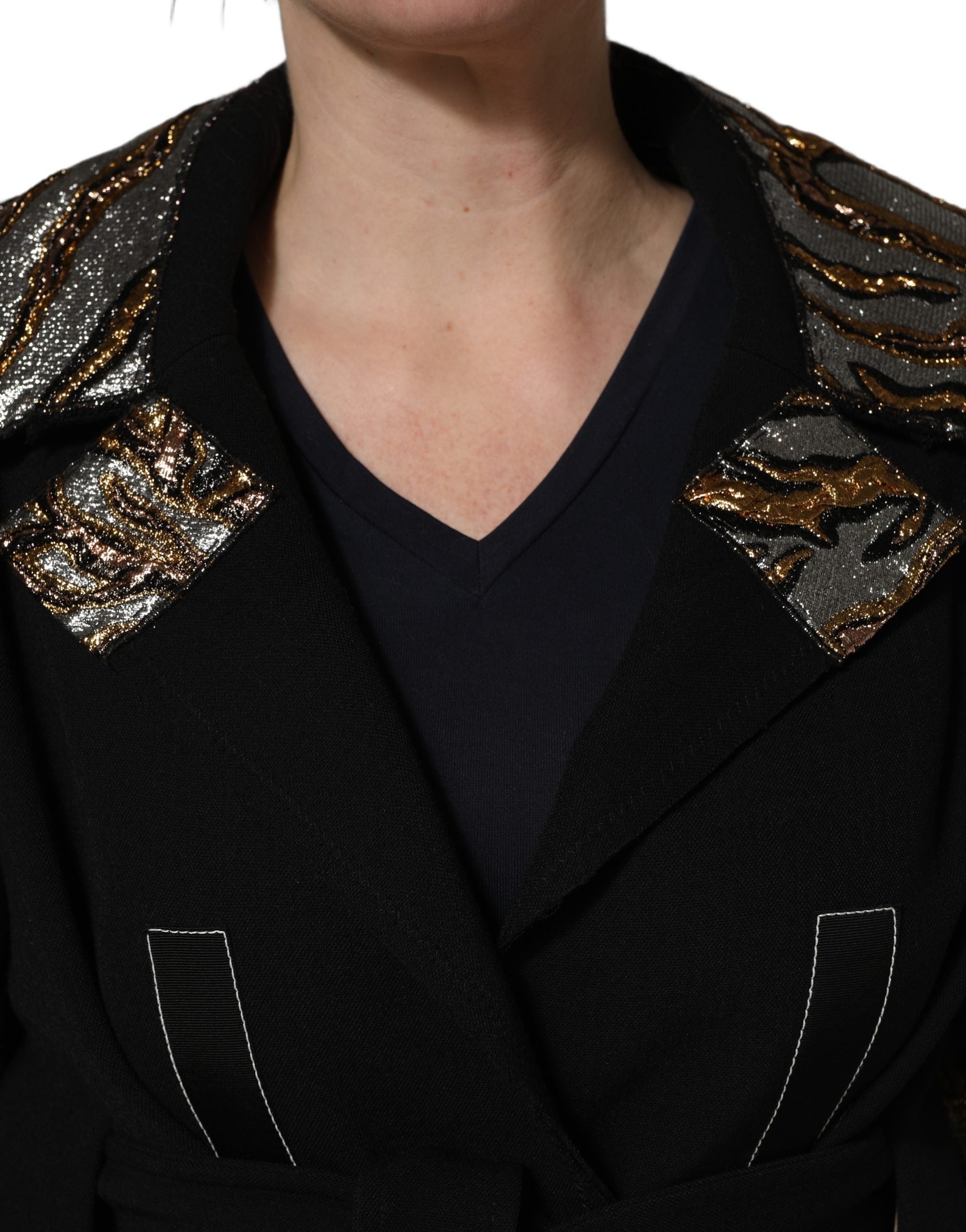 Manteau noir en brocart Dolce & Gabbana, ceinture à la taille, coupe simple et élégante, porté sur un fond neutre.