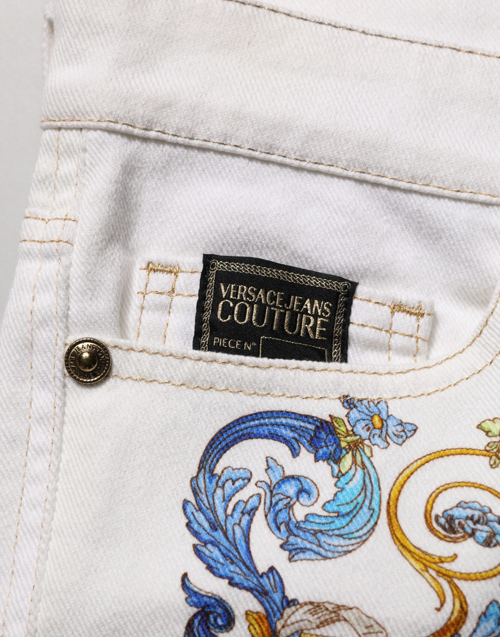Jeans skinny en denim blanc avec imprimé floral de Versace Jeans Couture, coupe ajustée et détails élégants.