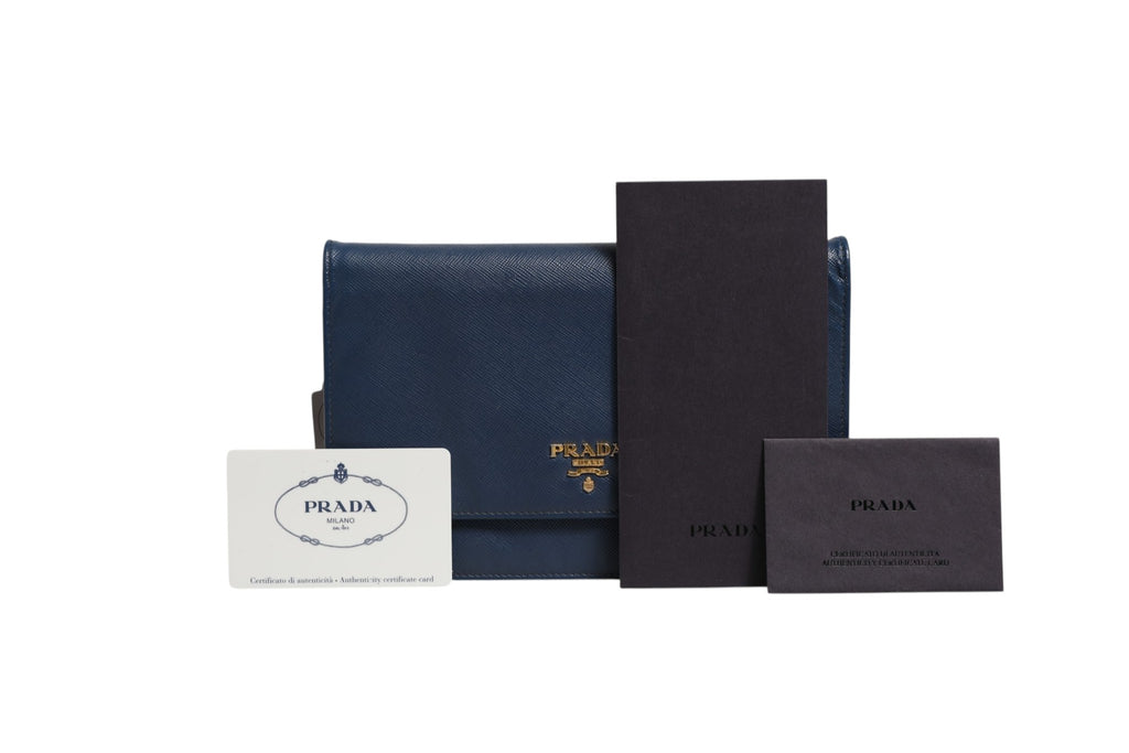 Pochette Prada en cuir Saffiano bleu avec chaîne, portefeuille et sac de soirée élégant, visible avec détails du cuir et de la chaîne.