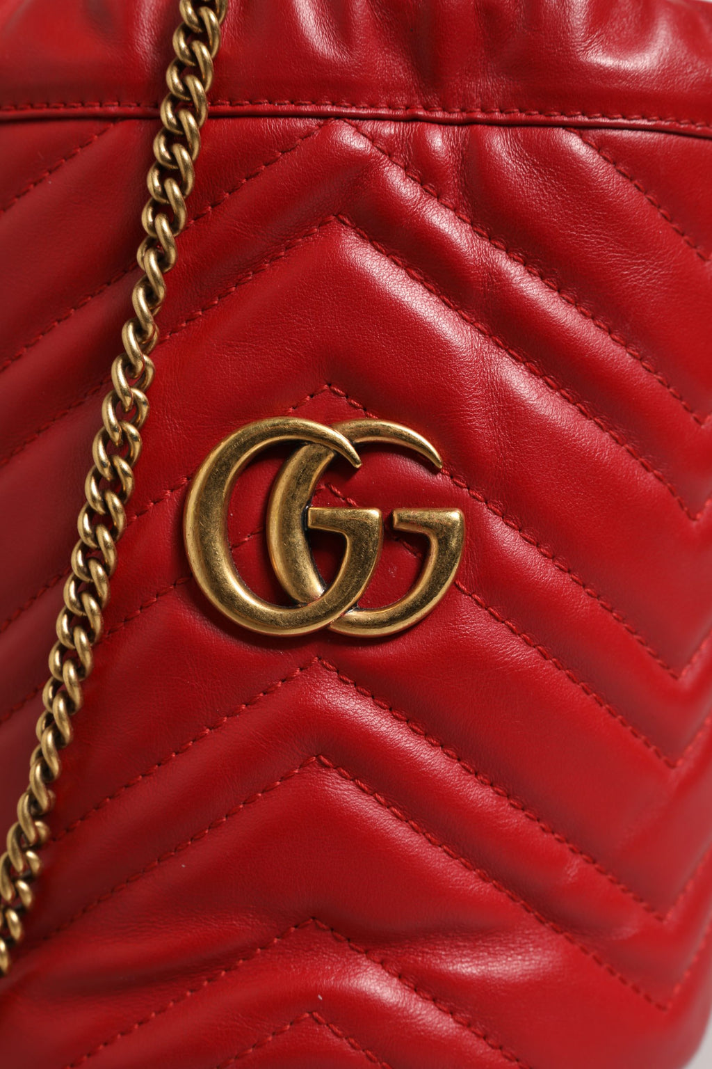 Sac seau Gucci GG Marmont en cuir de veau rouge à motif chevron matelassé, style élégant et tendance.