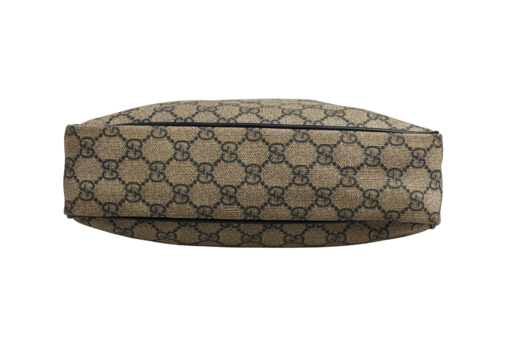 Sac messenger Gucci Supreme en toile avec détails en cuir, porté en bandoulière, visible avec logo Gucci sur le devant.