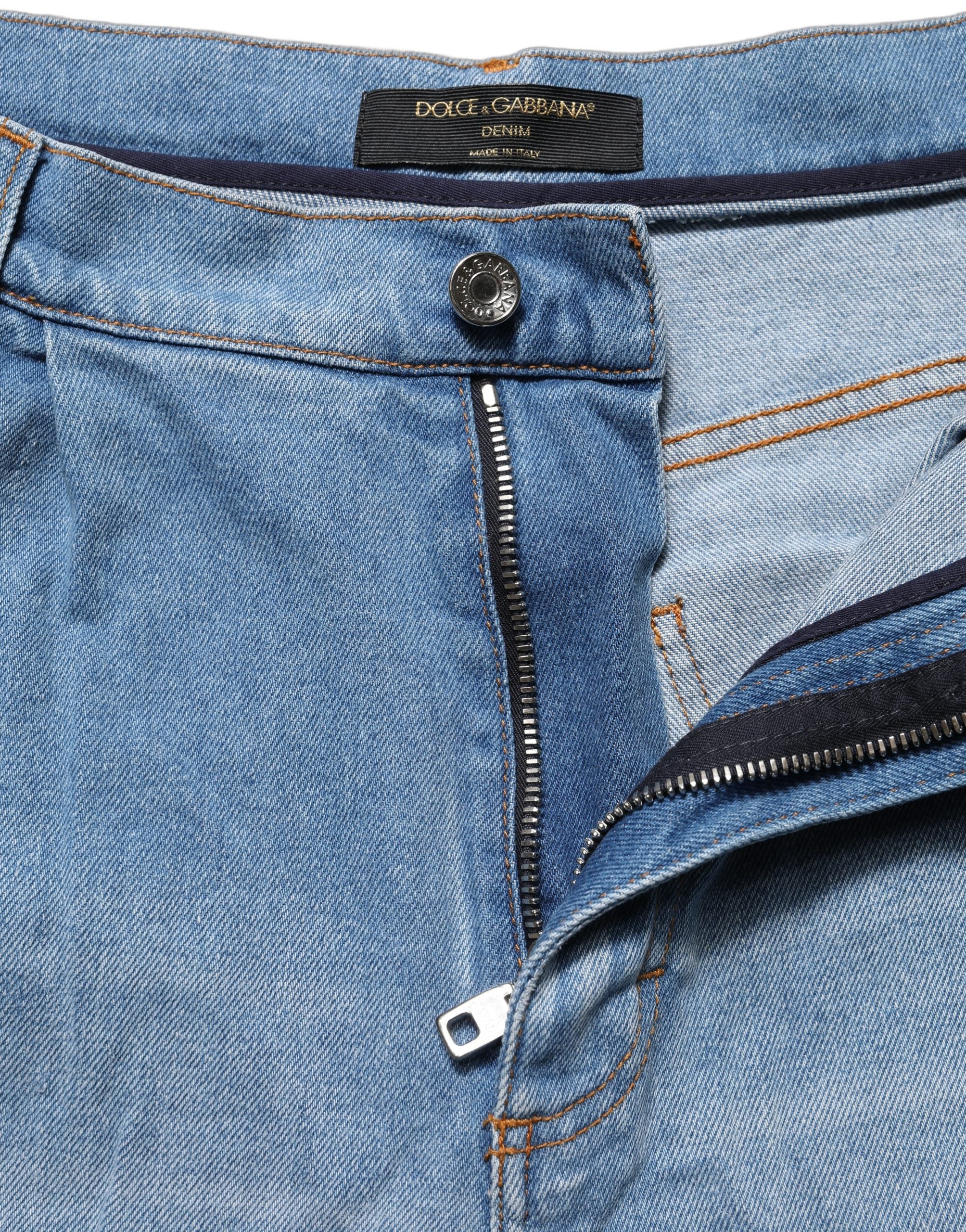 Jeans en denim coton bleu délavé avec plis, de la marque Dolce & Gabbana, visibles détails déchirés et usés.