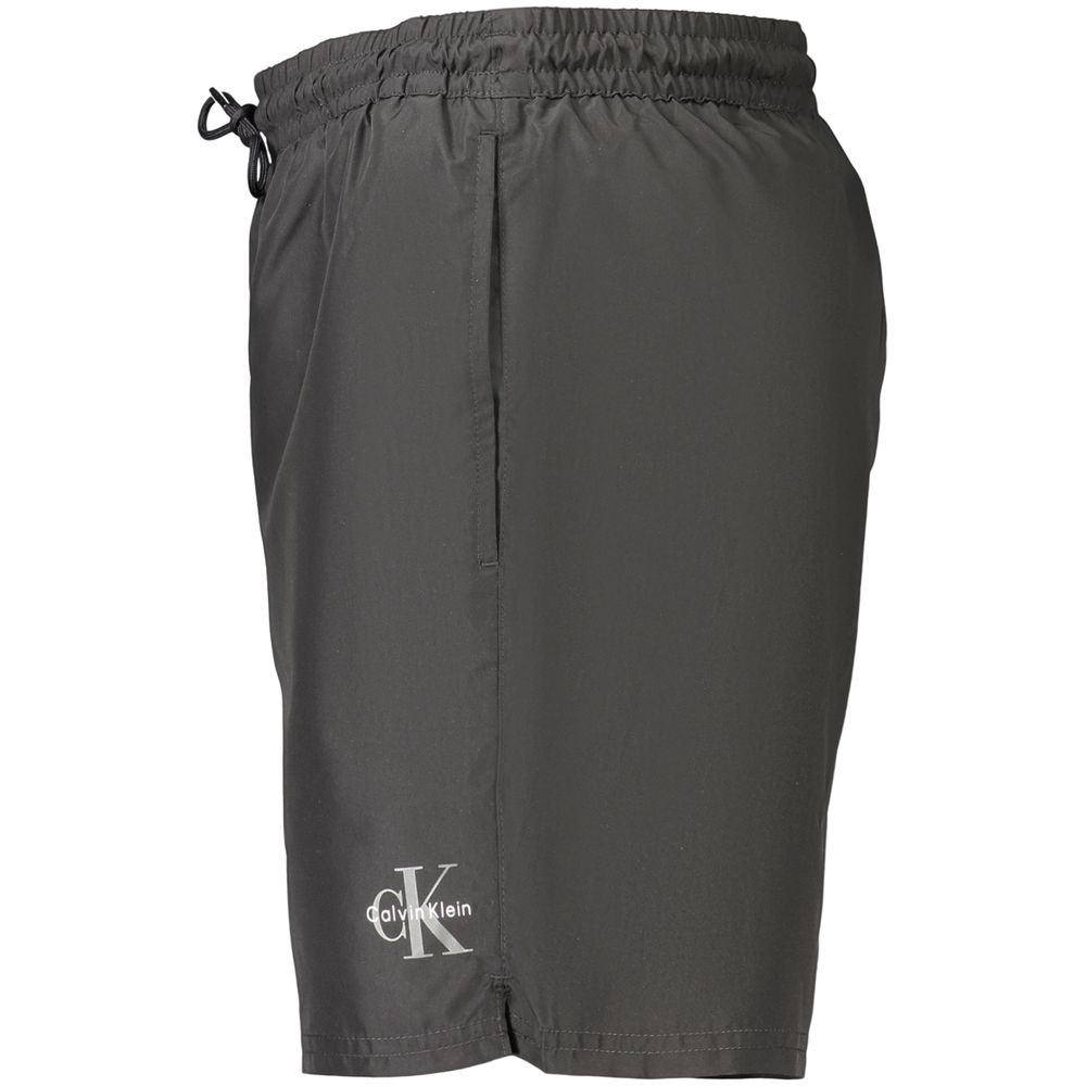 Maillot de bain homme en polyester noir de Calvin Klein, style classique et ajusté, visible avec ceinture élastique.
