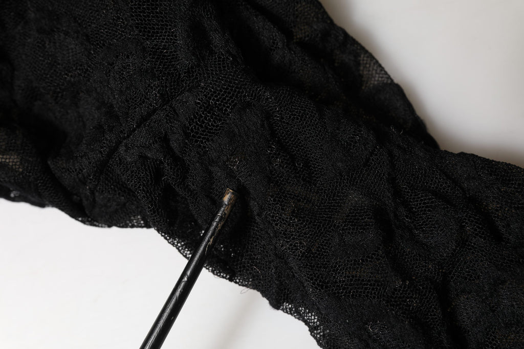 Top à manches longues en dentelle florale noire Dolce & Gabbana avec col roulé, élégance et détails raffinés visibles sur l'image.