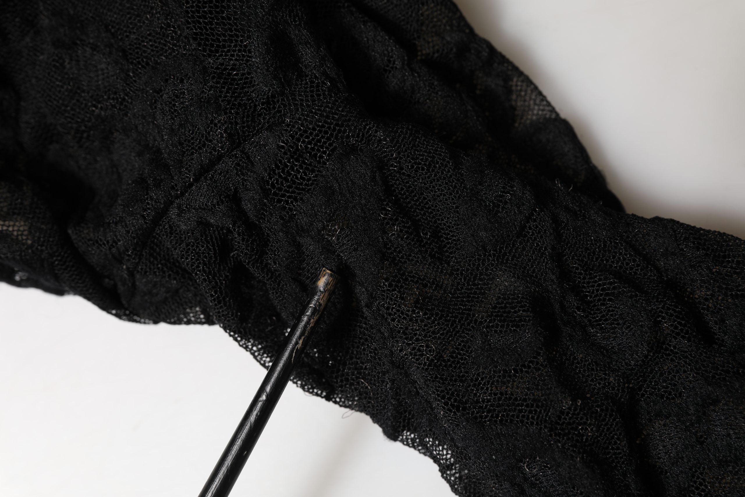 Top à manches longues en dentelle florale noire Dolce & Gabbana avec col roulé, élégance et détails raffinés visibles sur l'image.