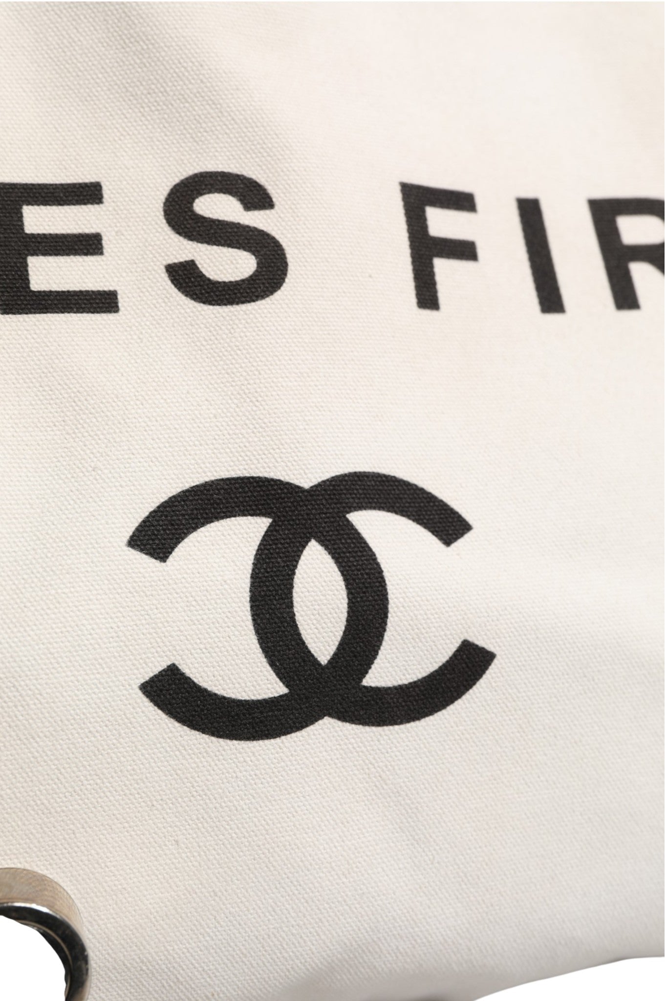 Sac à main Chanel Ladies First en toile blanche et noire, tote élégant pour femmes, avec logo Chanel visible.