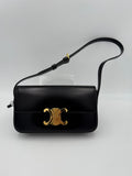 Sac à main Celine Claude Triomphe noir, en cuir, avec logo élégant, porté sur une épaule, vue de face.