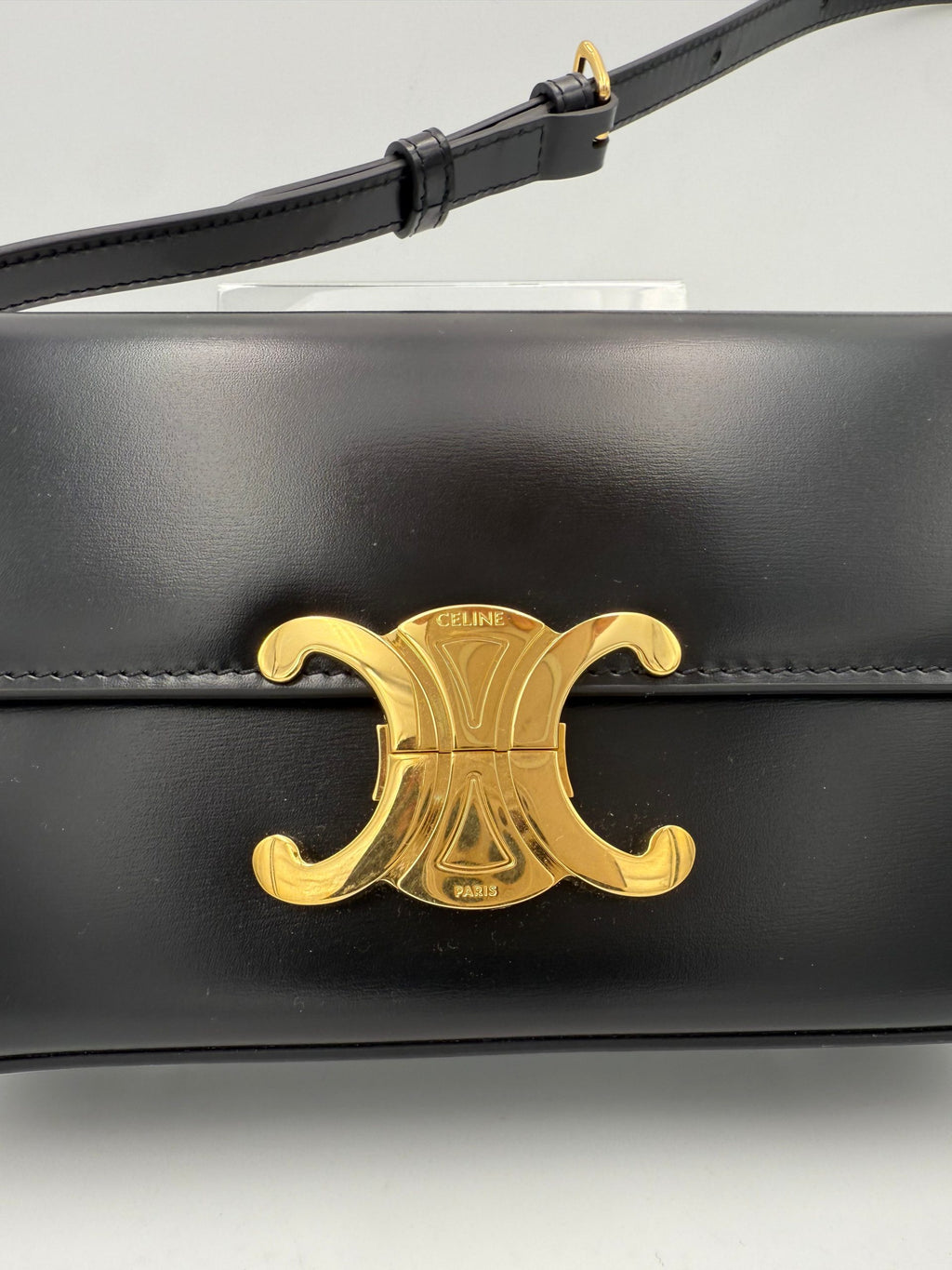 Sac à main noir Celine Claude Trapeze, élégant et spacieux, avec détails en métal doré et logo Celine visible sur la façade.