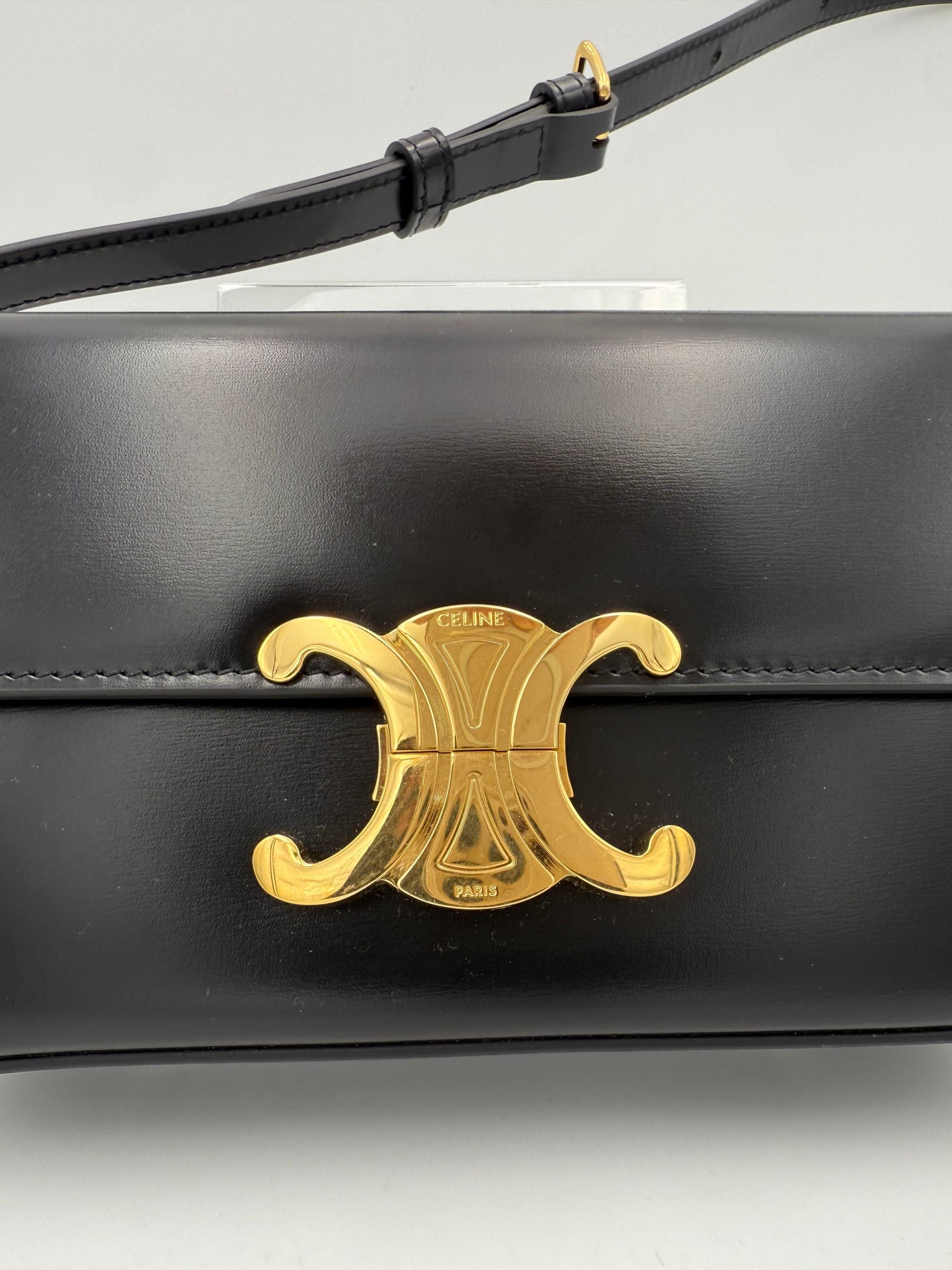 Sac à main noir Celine Claude Trapeze, élégant et spacieux, avec détails en métal doré et logo Celine visible sur la façade.