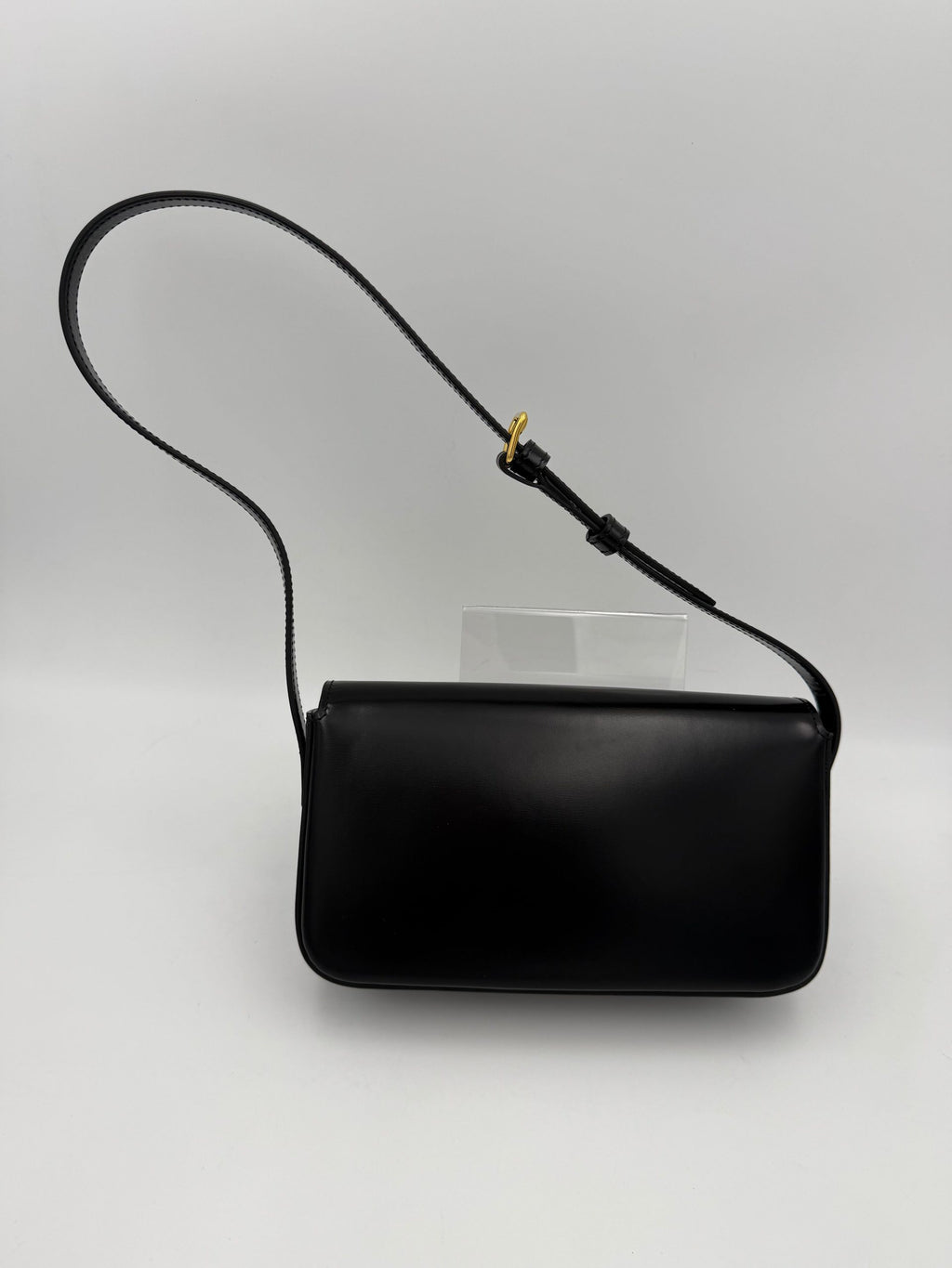 Sac à main noir Celine Claude Trapeze avec logo triomphe, en cuir, élégant et spacieux, visible sur l'image.