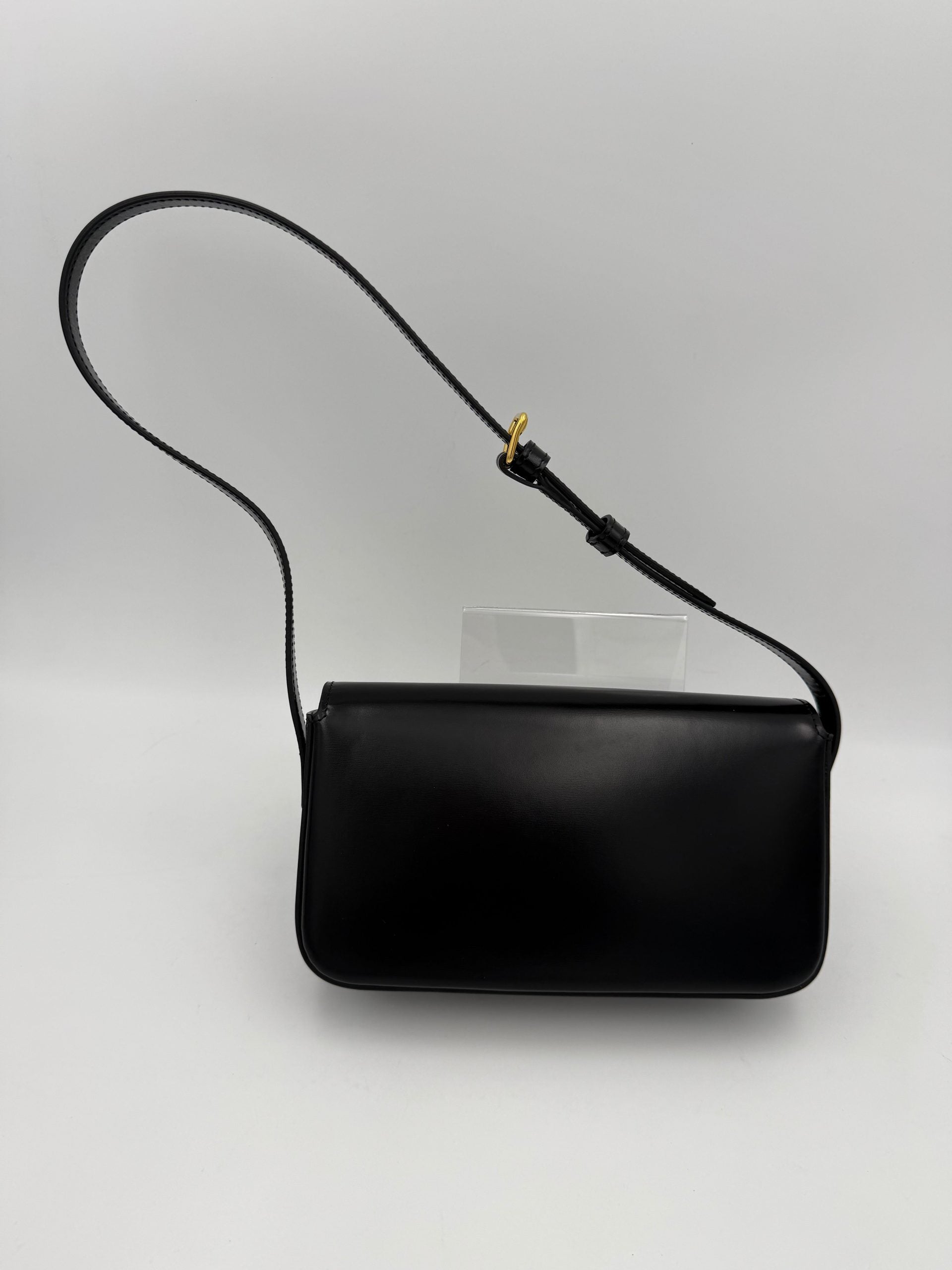 Sac à main noir Celine Claude Trapeze avec logo triomphe, en cuir, élégant et spacieux, visible sur l'image.