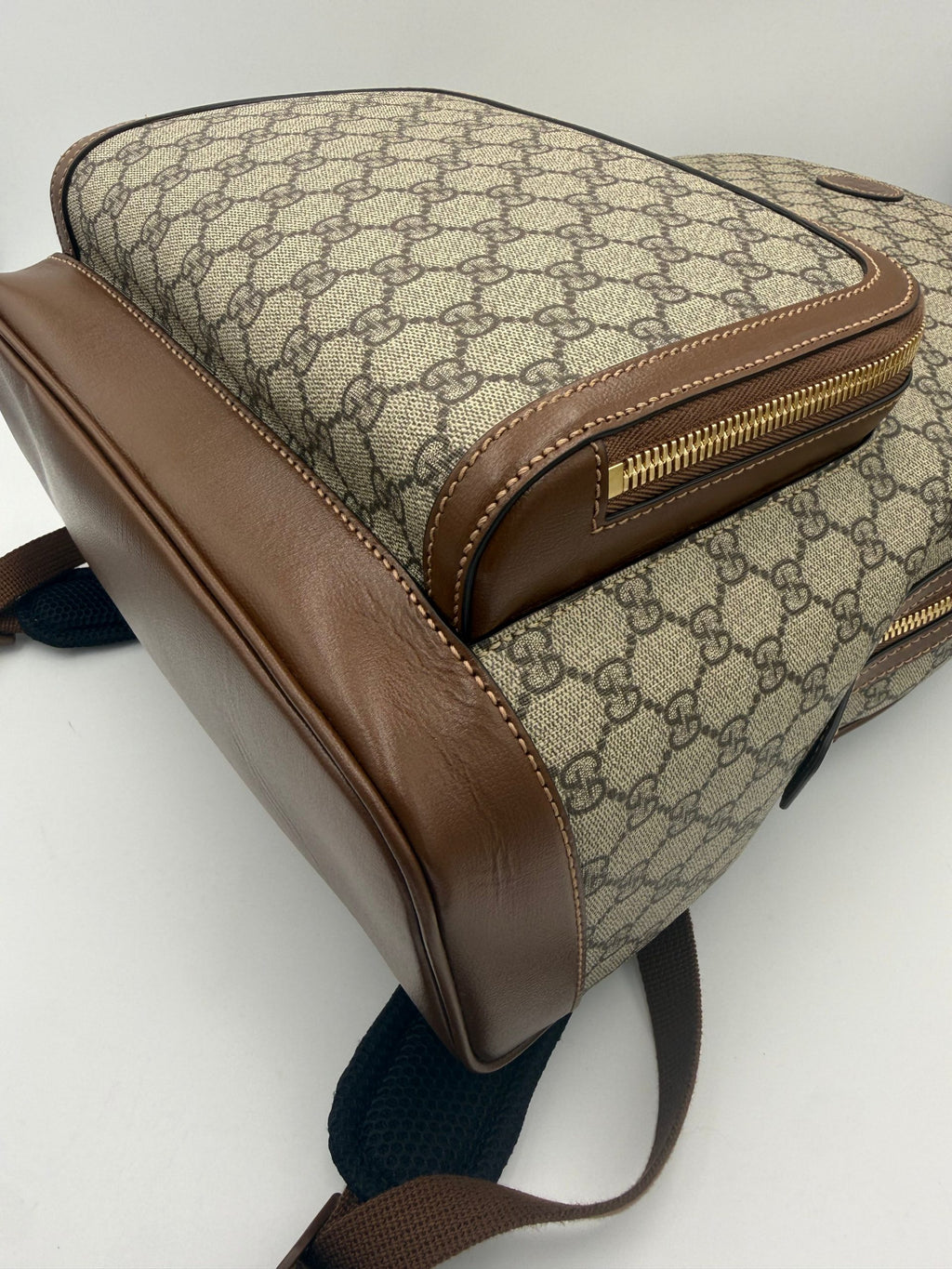 Sac à dos Gucci GG Supreme et cuir, avec logo emblématique, poignées en cuir et détails élégants visibles sur l'image.