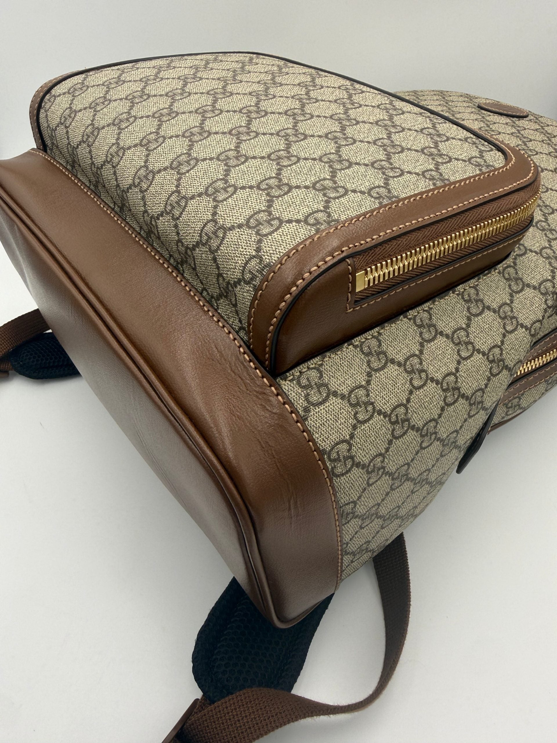 Sac à dos Gucci GG Supreme et cuir, avec logo emblématique, poignées en cuir et détails élégants visibles sur l'image.