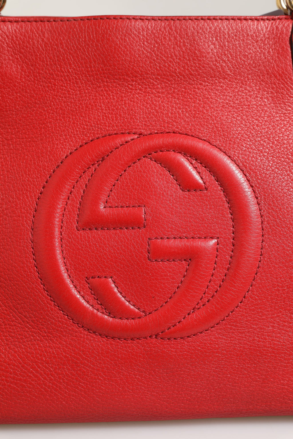 Sac Gucci Soho en cuir petite, avec poignées doubles et logo Gucci, posé sur une surface en bois, vue de face.