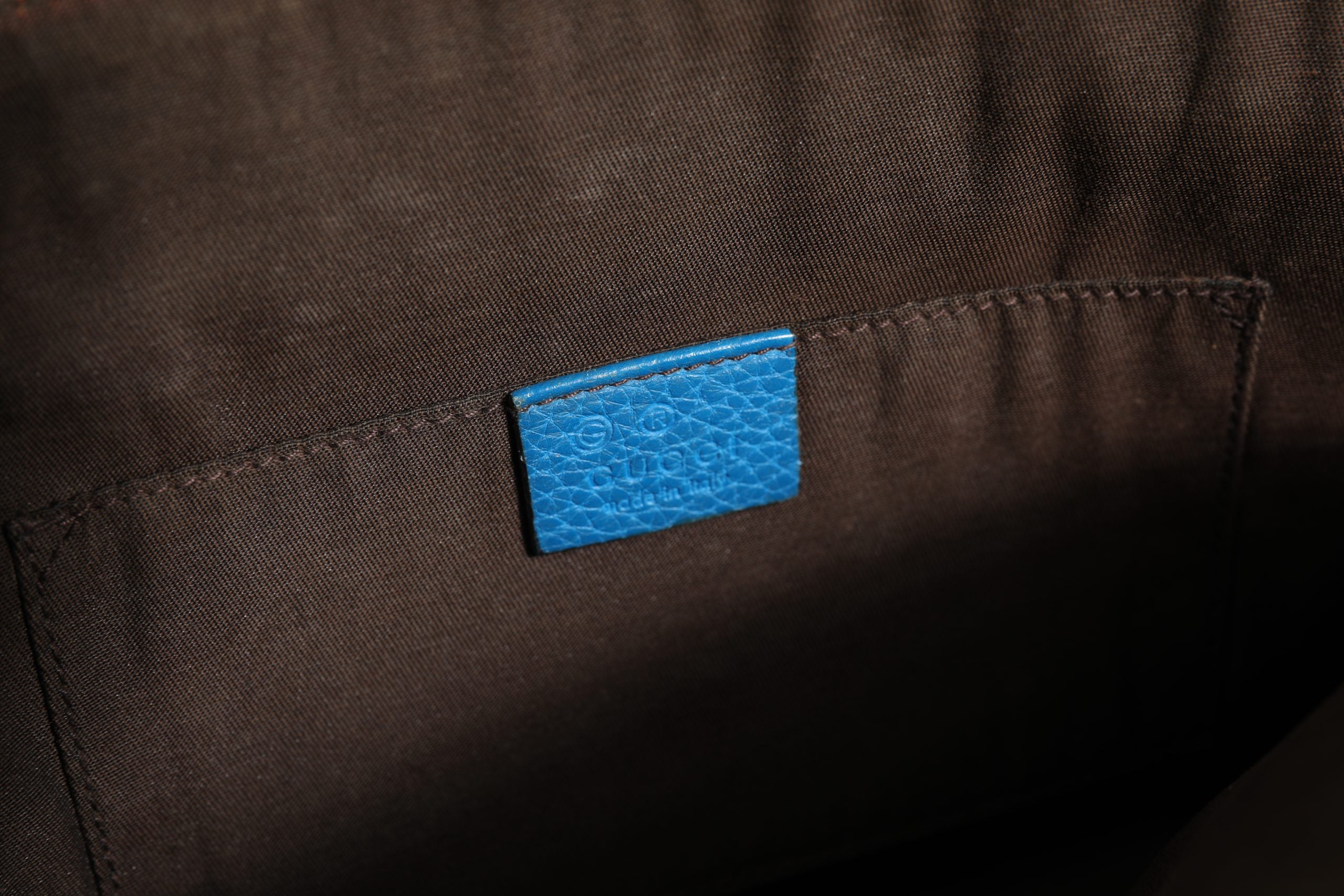 Sac à main en cuir bleu Gucci, forme arrondie avec poignée en cuir, détails élégants et logo Gucci visible.