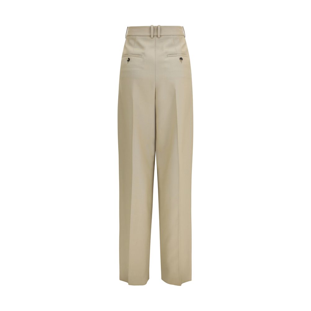 Pantalon beige en laine Saint Laurent Oves Aries, coupe élégante, détails de couture visibles, porté avec une chemise blanche.