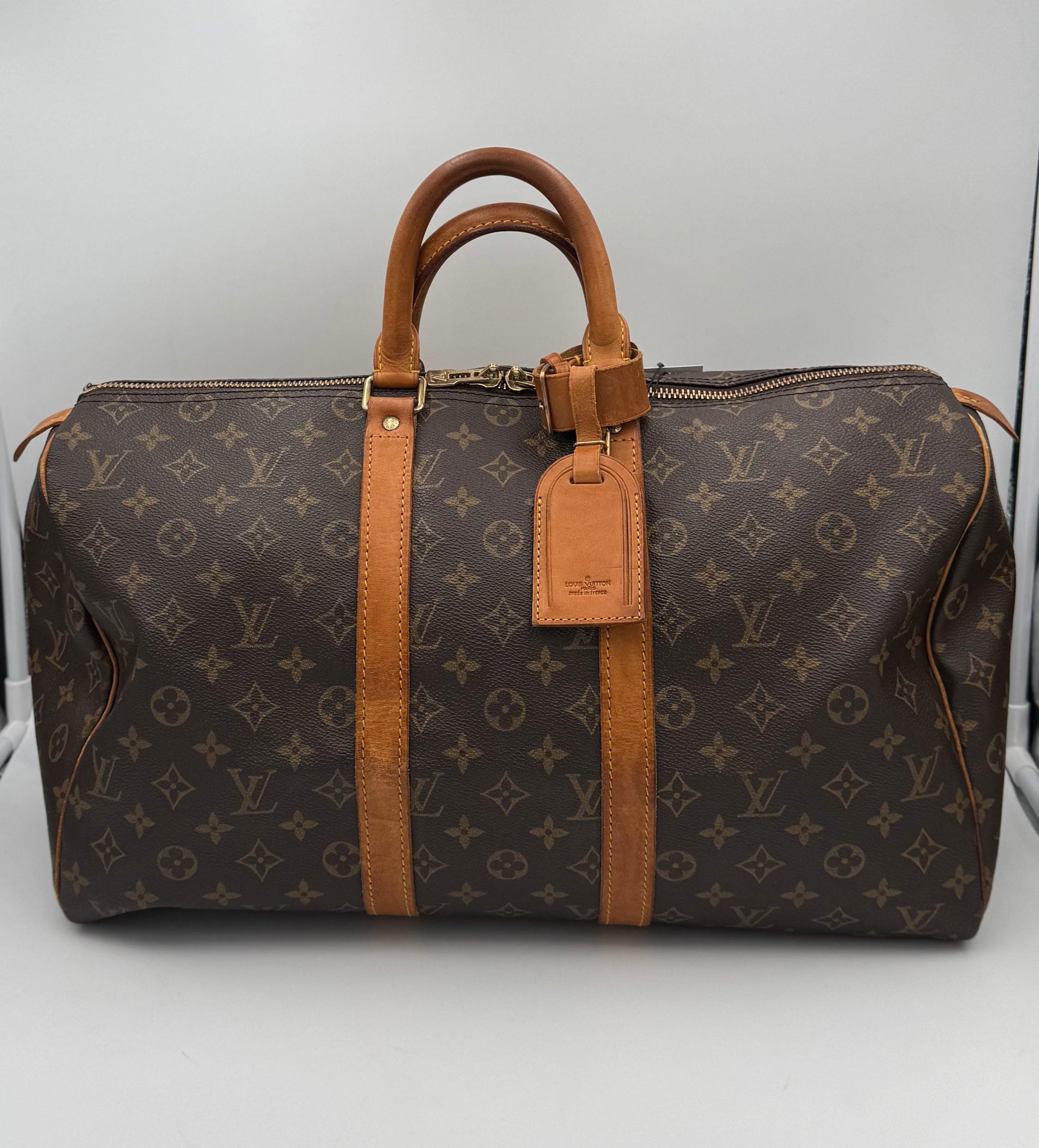 Sac à main Louis Vuitton Keepall 45 en toile Monogram avec poignées en cuir et fermeture zippée visible.