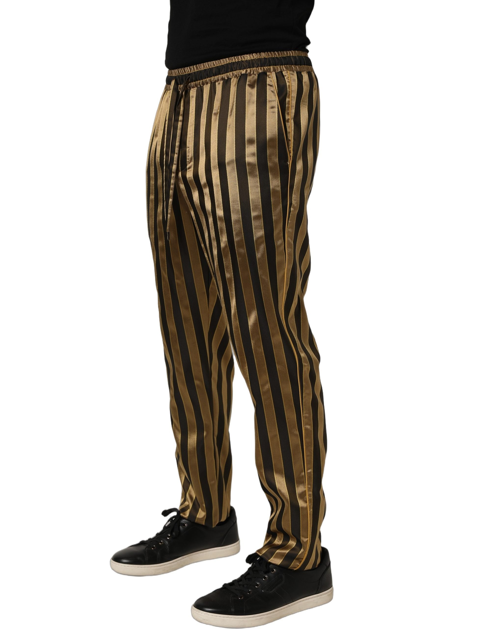Pantalons homme Dolce & Gabbana en satin noir et or avec rayures, coupe tapered, style élégant et sophistiqué.