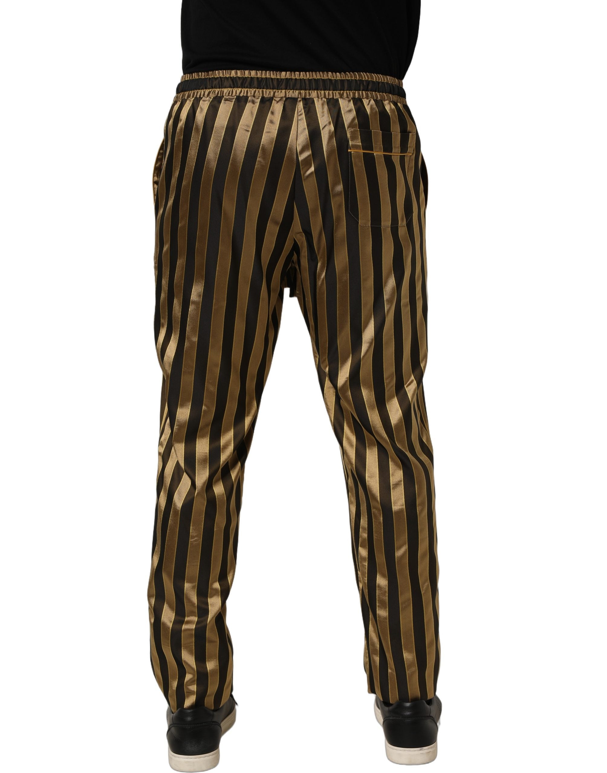 Pantalon homme Dolce & Gabbana en satin noir et or à rayures, coupe tapered, style élégant et sophistiqué.