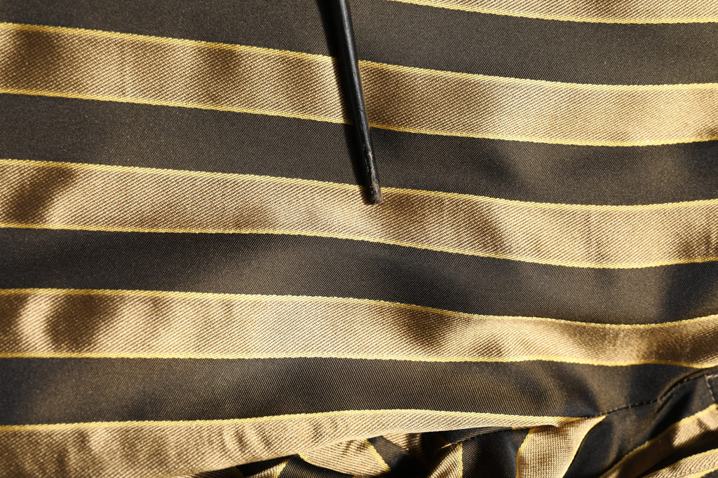 Pantalons en satin noir à rayures dorées et noires de Dolce & Gabbana, coupe tapered, style élégant et sophistiqué.