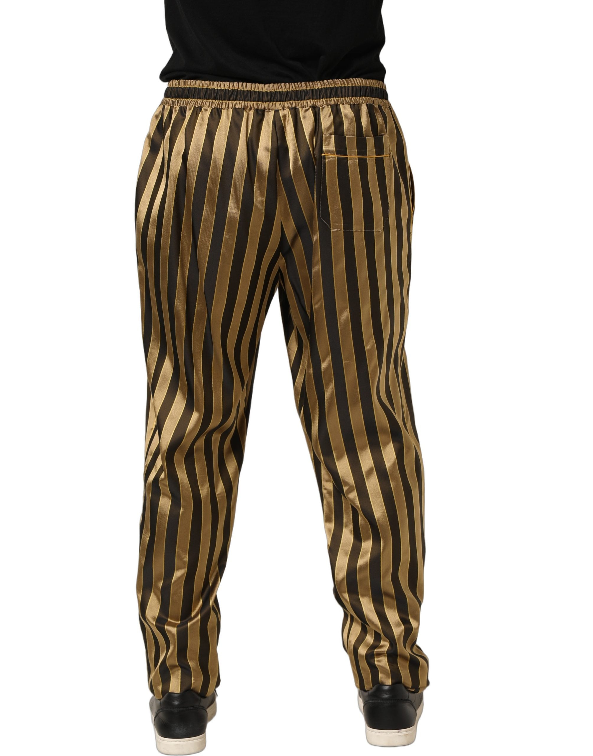 Pantalon en satin noir et or à rayures Dolce & Gabbana, coupe tapered, jambes fuselées et détails élégants.