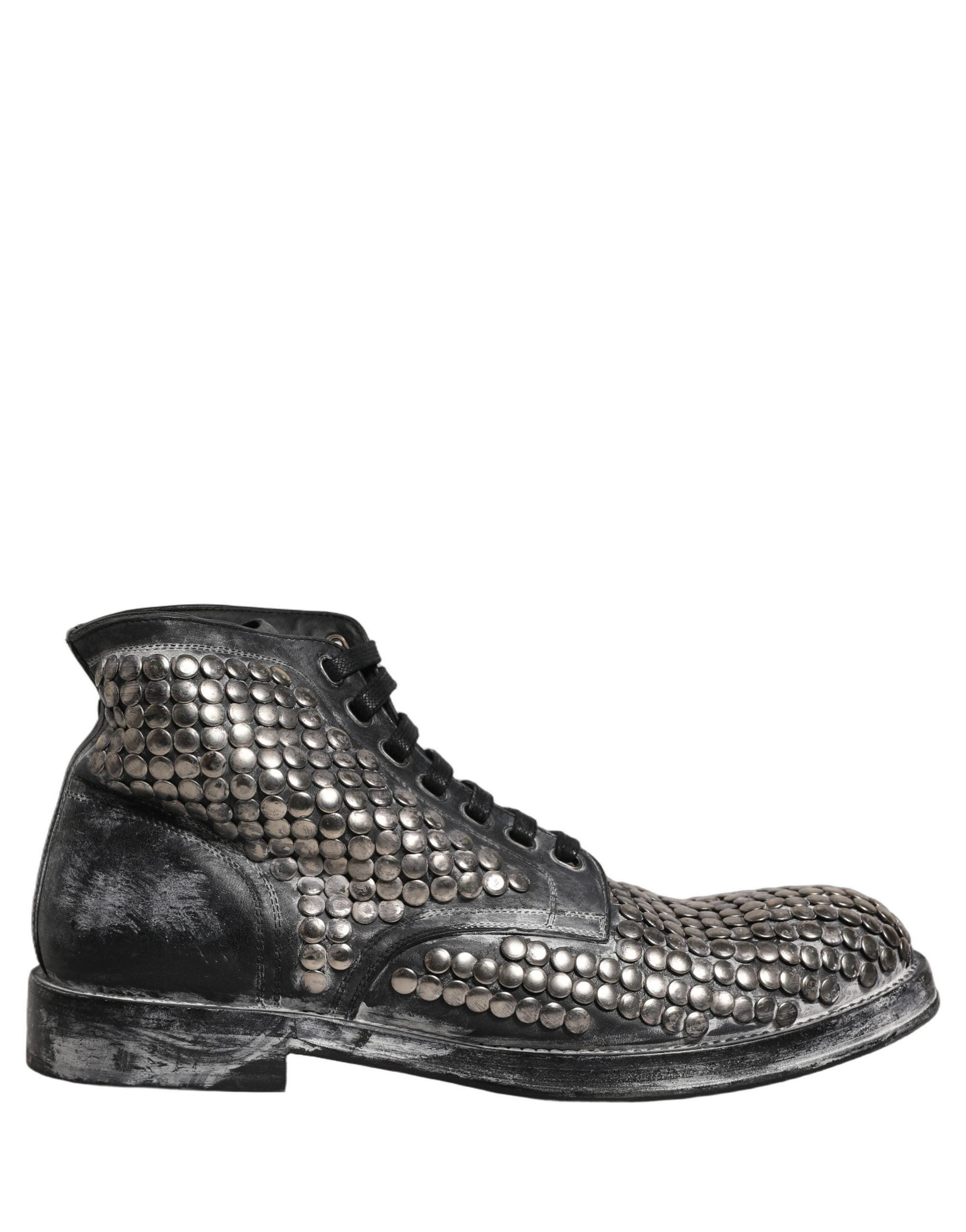 Bottes ankle en cuir noir Dolce & Gabbana avec studs, style runway, visibles en gros plan sur l'image.