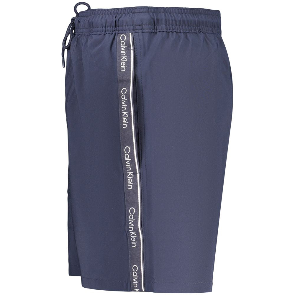 Shorts de bain pour hommes en polyester bleu de Calvin Klein, avec logo visible, parfait pour la plage ou la piscine.