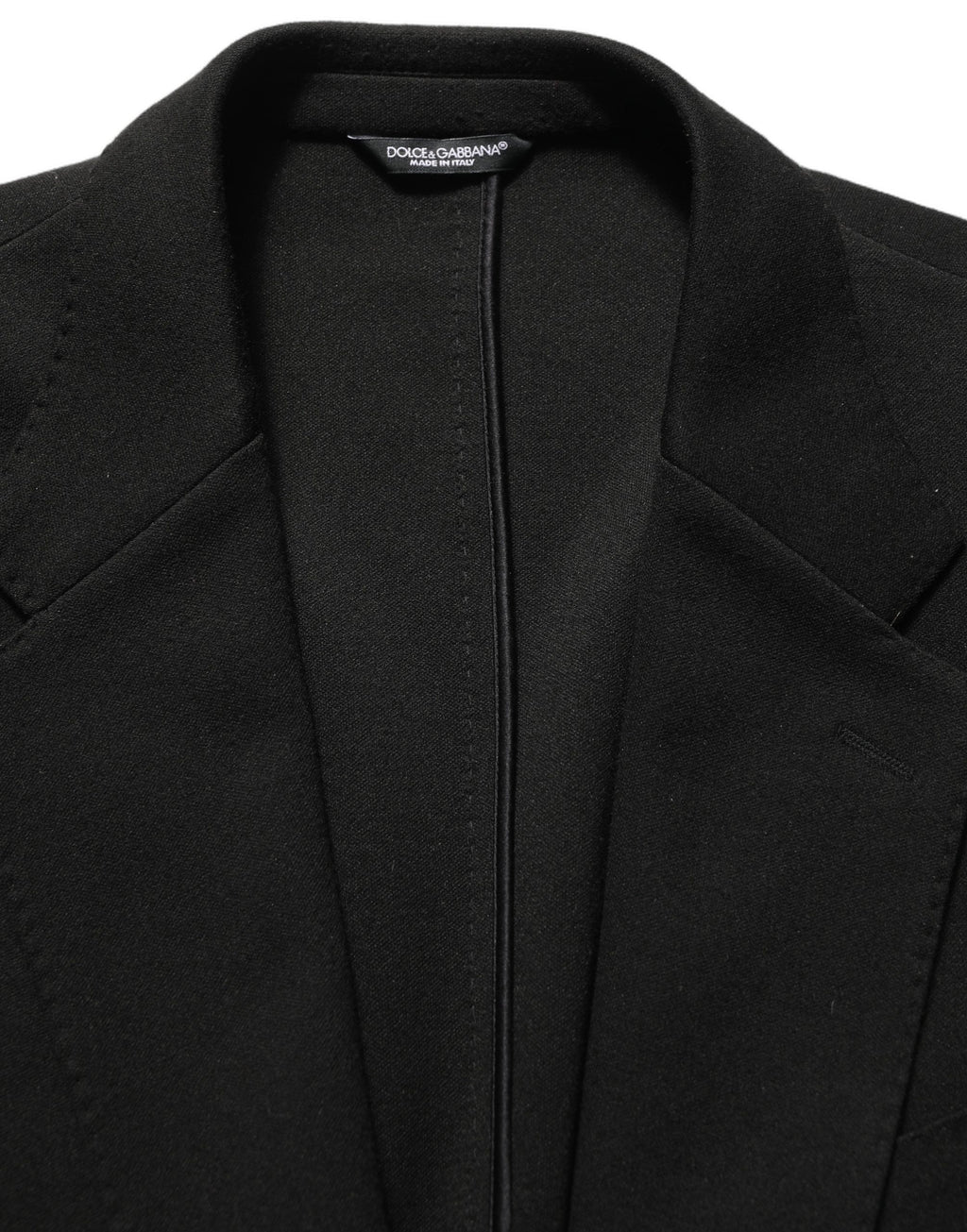 Manteau blazer noir Dolce & Gabbana avec logo, col cranté, à simple boutonnage, porté sur un fond neutre.