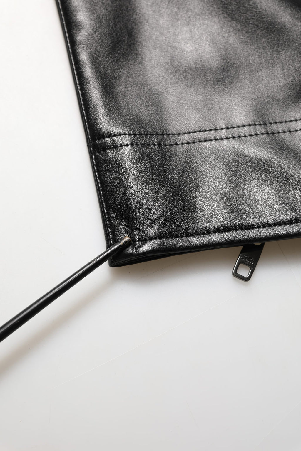 Pantalon homme en cuir synthétique noir avec fermeture éclair de la marque Dolce & Gabbana, style élégant et moderne.