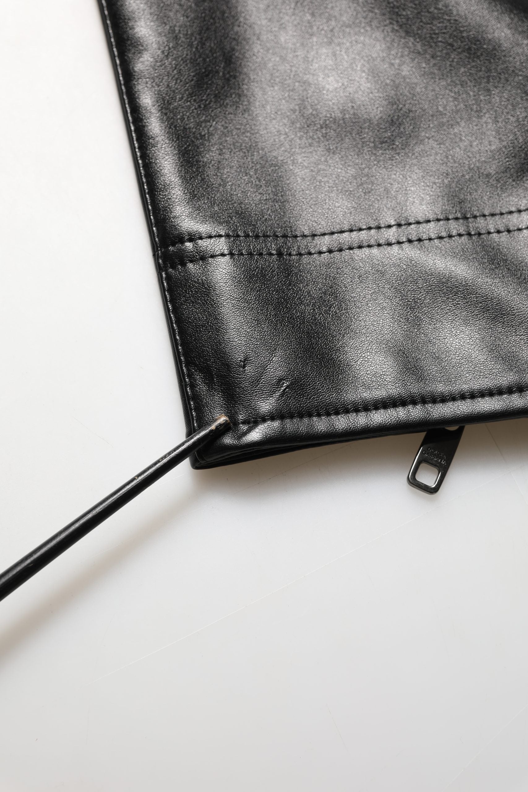 Pantalon homme en cuir synthétique noir avec fermeture éclair de la marque Dolce & Gabbana, style élégant et moderne.