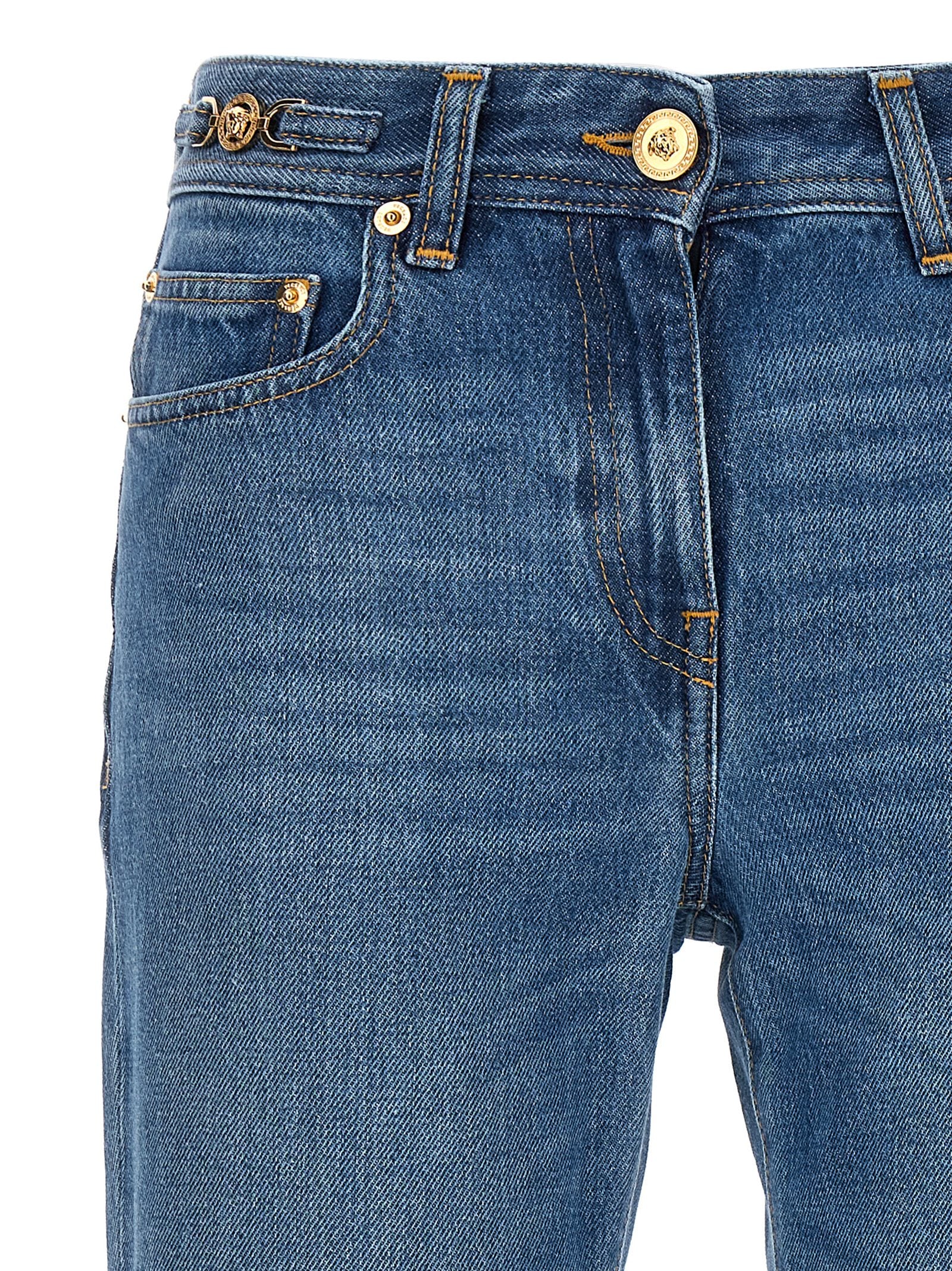 Jeans évasés en coton bleu de la marque Versace, coupe tendance, détails de couture visibles.