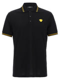 Chemise polo en coton noir de la marque Versace, avec logo distinctif visible sur la poitrine.