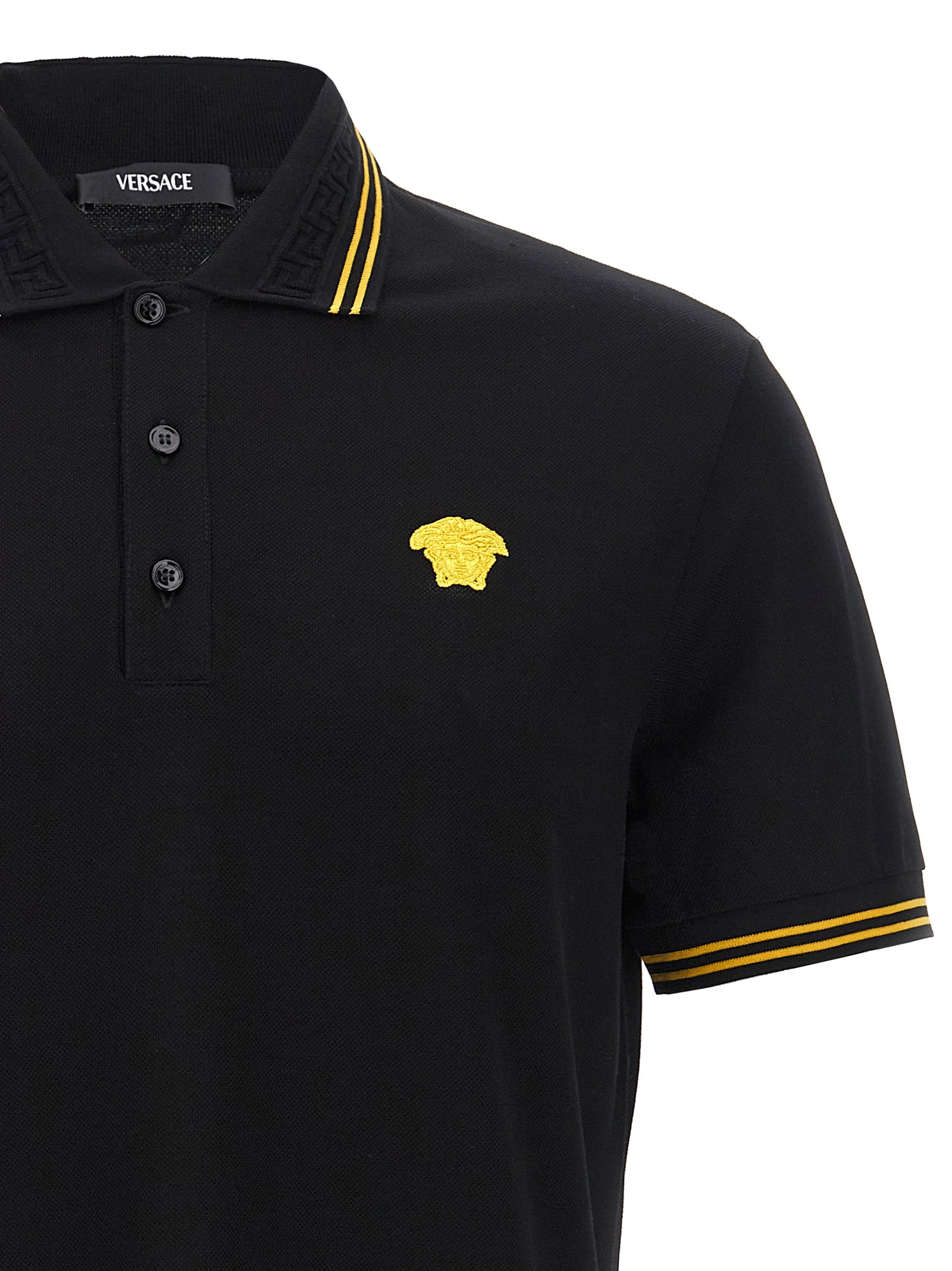 Chemise polo noire en coton de la marque Versace, avec logo emblématique visible sur la poitrine.