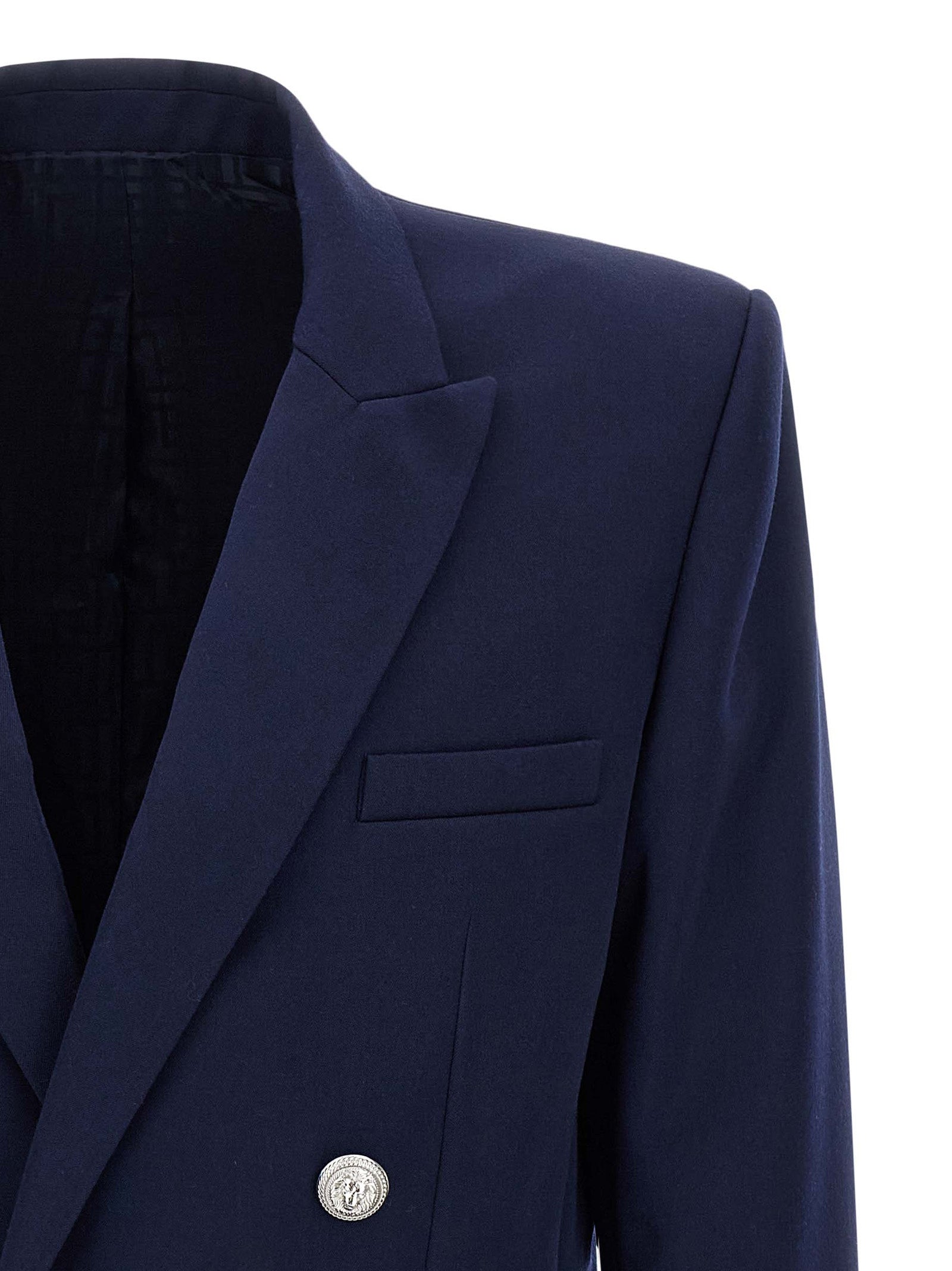 Blazer bleu en laine vierge Balmain, coupe élégante, détails sophistiqués et logo Balmain visibles sur l'image.