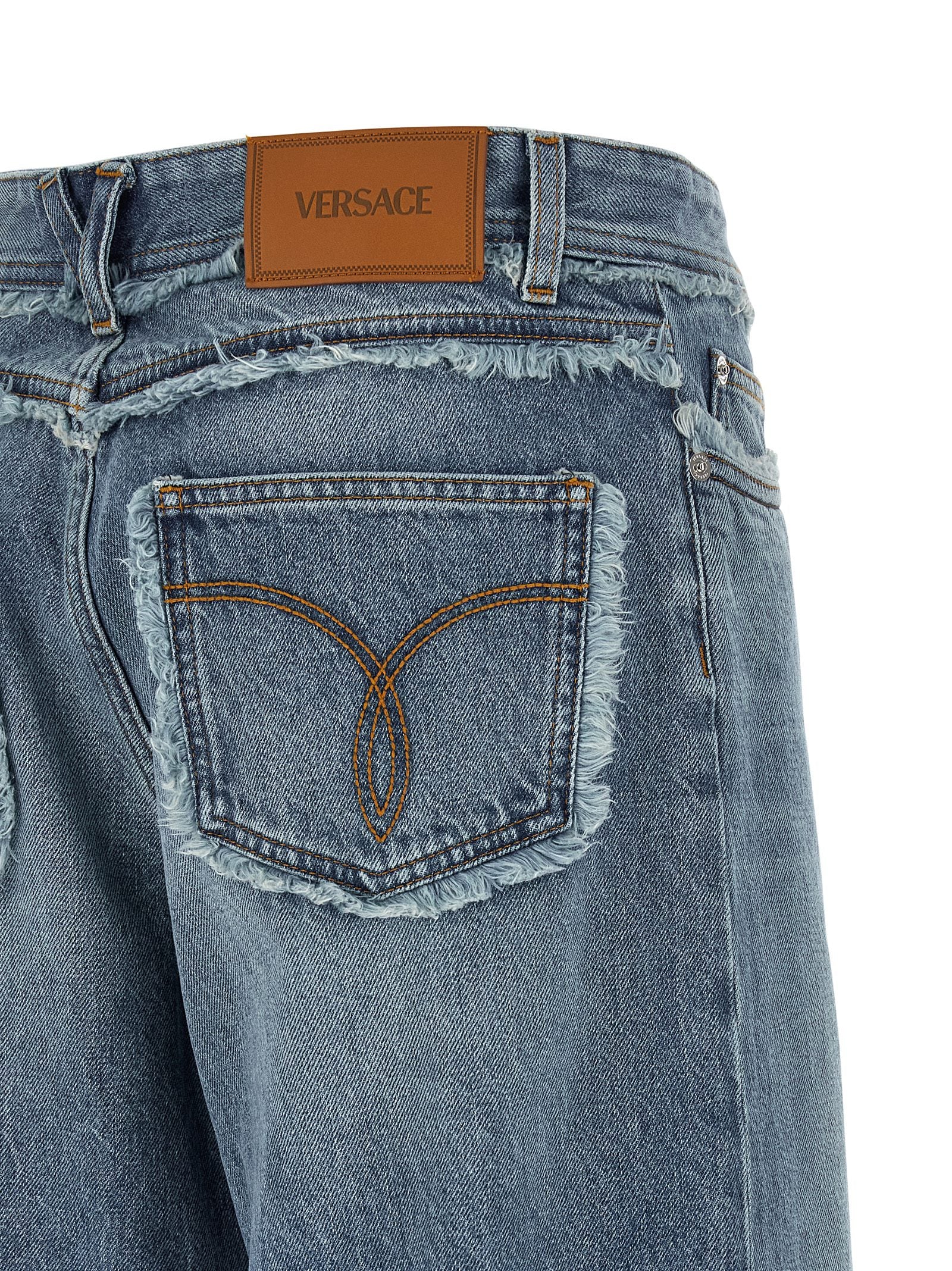 Jeans boyfriend en coton bleu Versace, coupe décontractée, avec détails de marque visibles, porté sur un mannequin.
